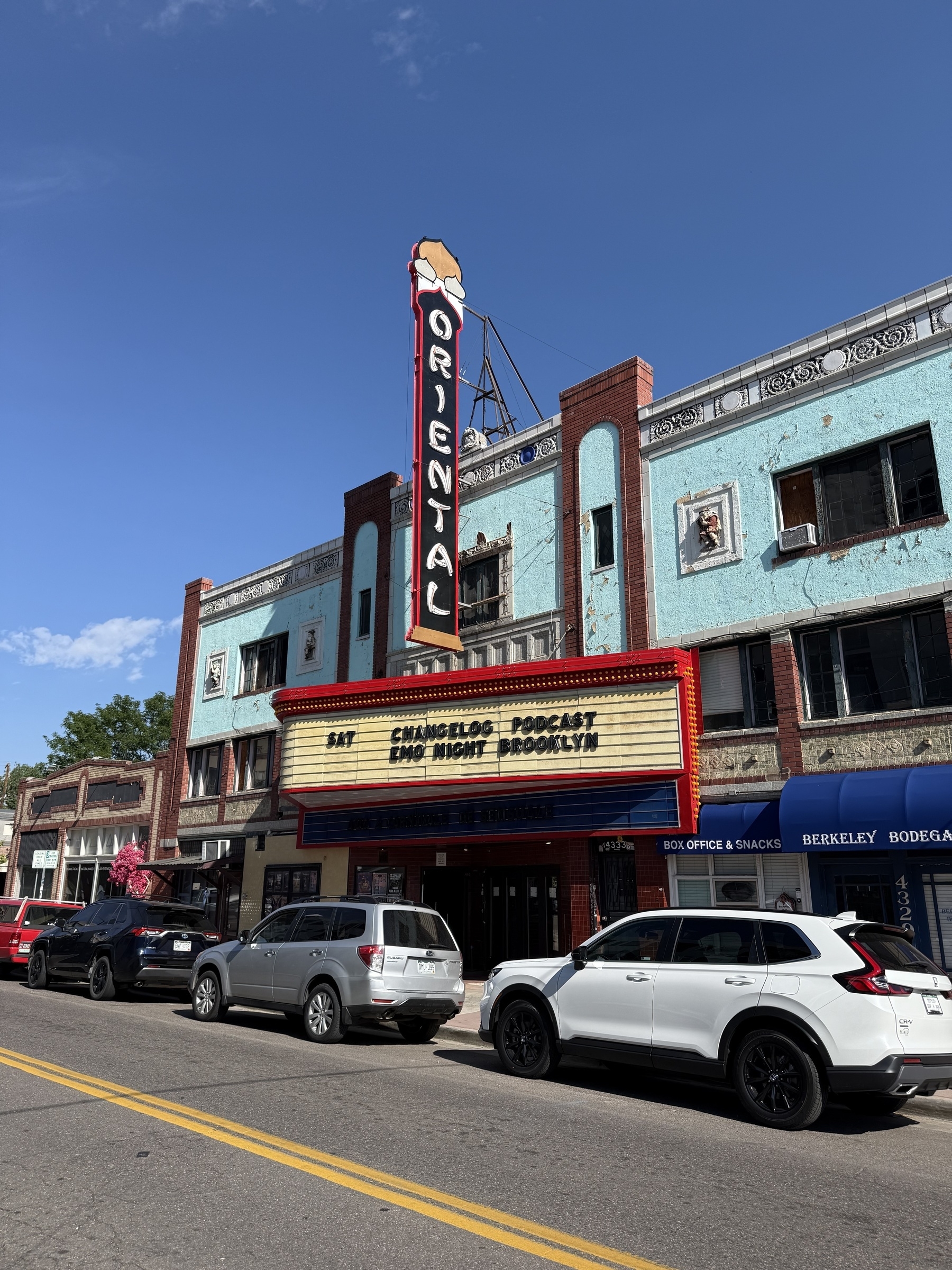 Auto-generated description: A historic theater with a sign reading Oriental is located on a street lined with parked cars.