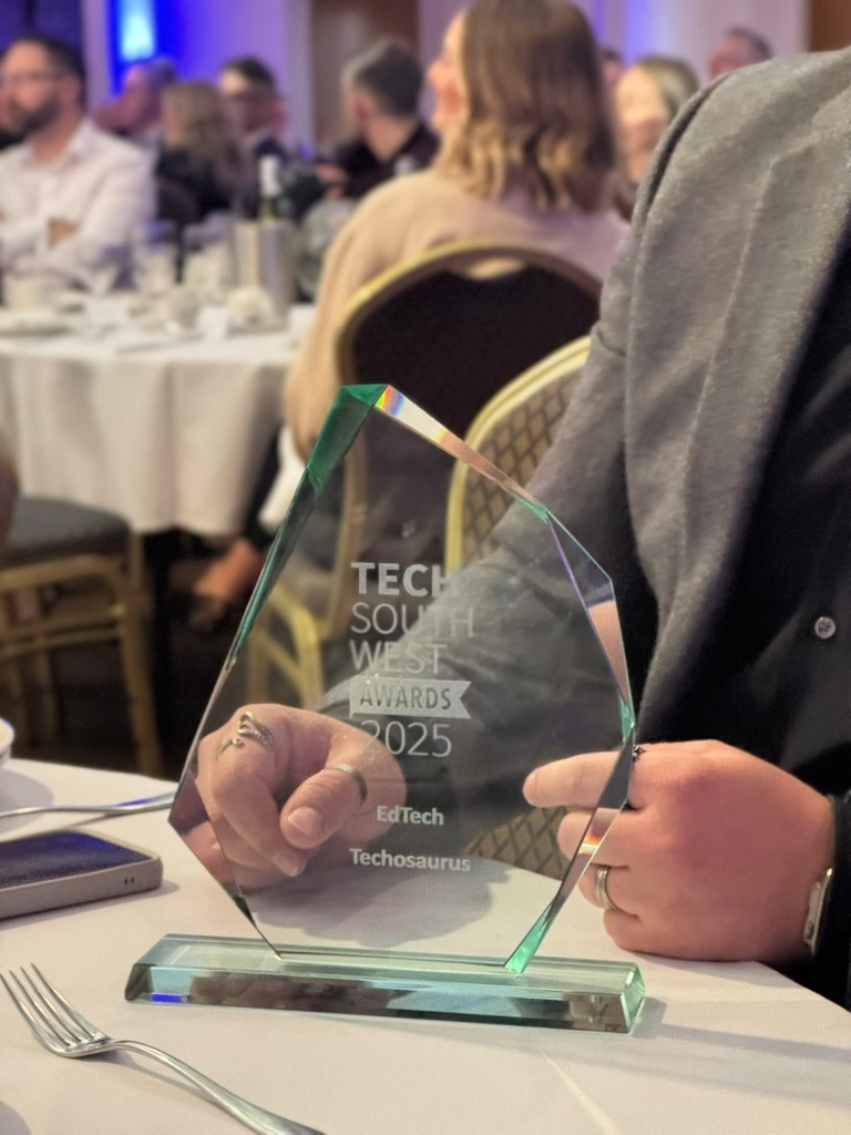 Auto-generated description: A person is holding a glass award with the inscription Tech South West Awards 2025 at a banquet event.