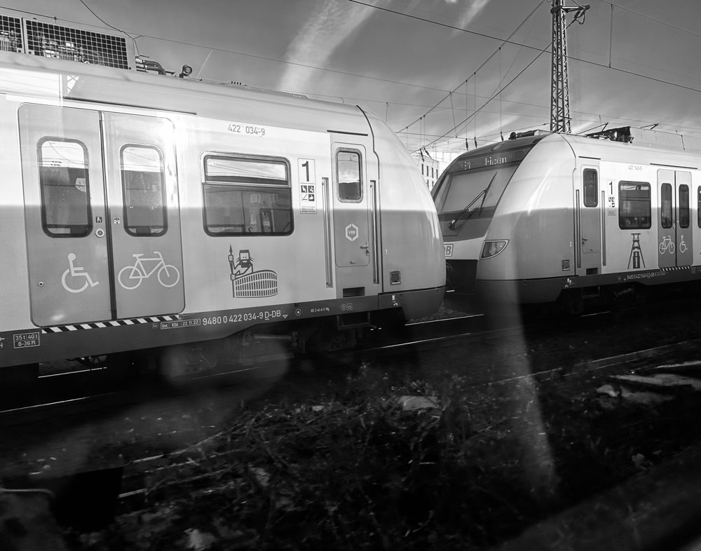 Picture of a train riding on the tracks taken through window of another train running parallel.