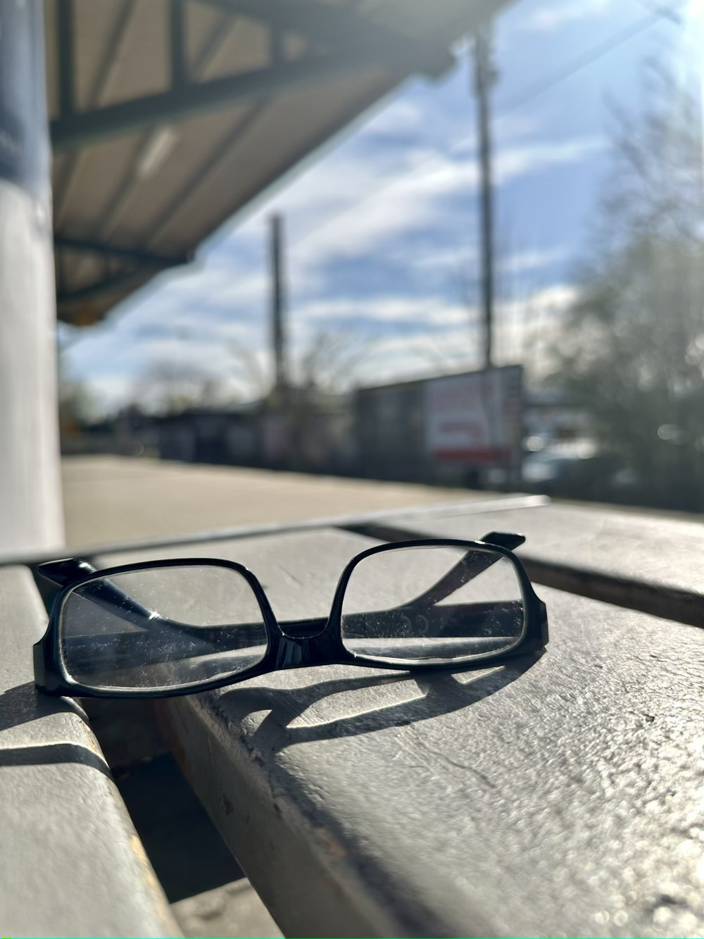 Pair of glasses sitting forgotten on a bench.