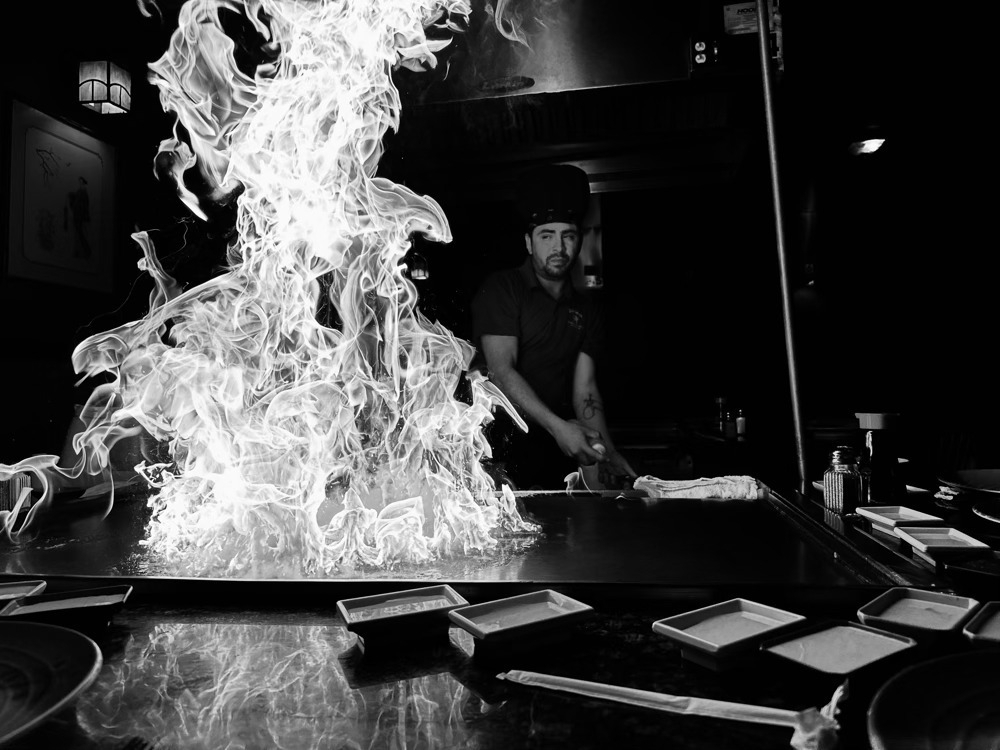 Hibachi chef starting fire on the grill.
