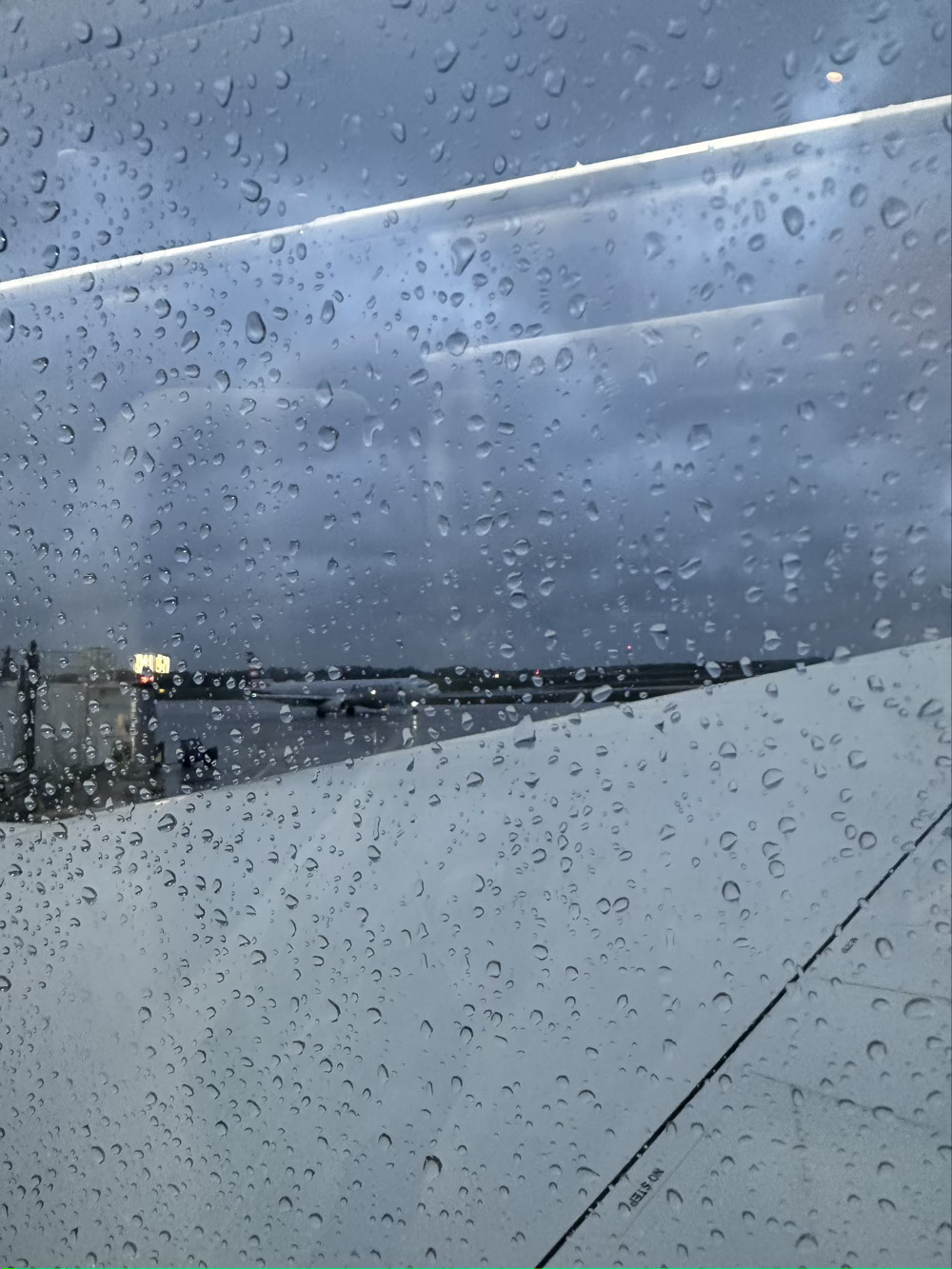 Raindrops on window with plane taxiing in the background.