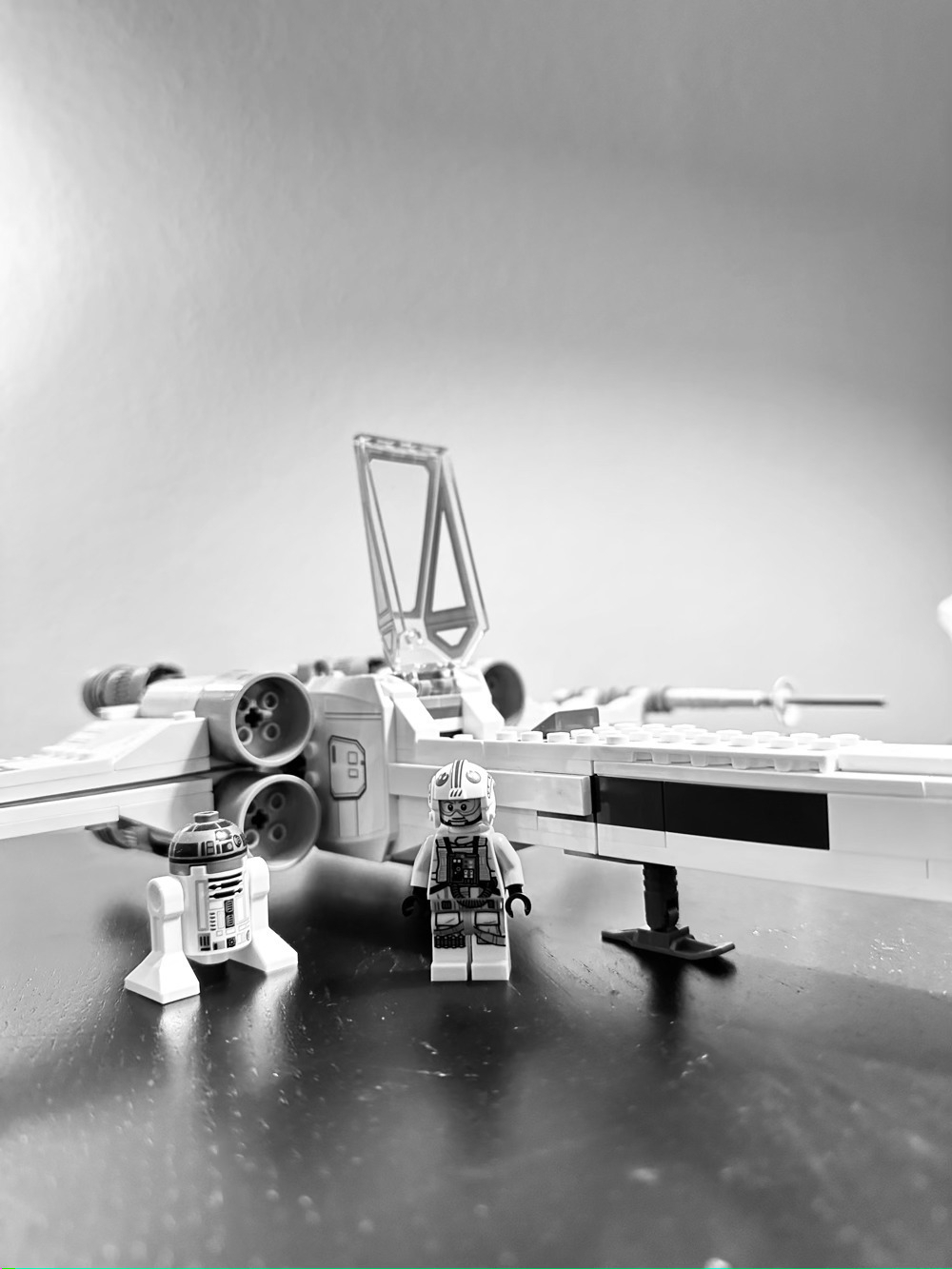 Lego figure of Luke Skywalker and R2-D2 standing in front of a Lego X-Wing fighter.