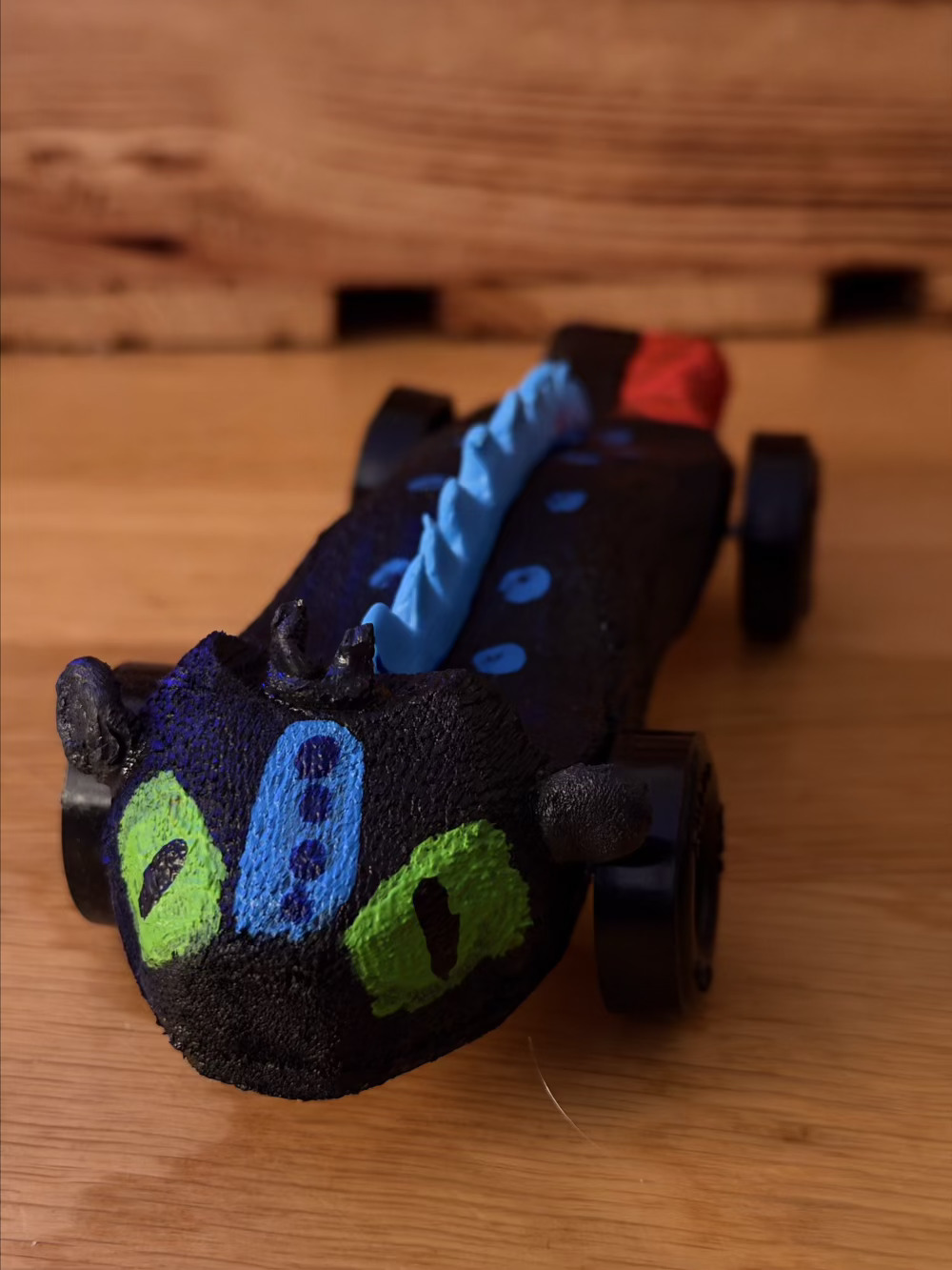 Picture of a pinewood derby car decorated to look like the dragon Toothless from the movie How to Train Your Dragon 