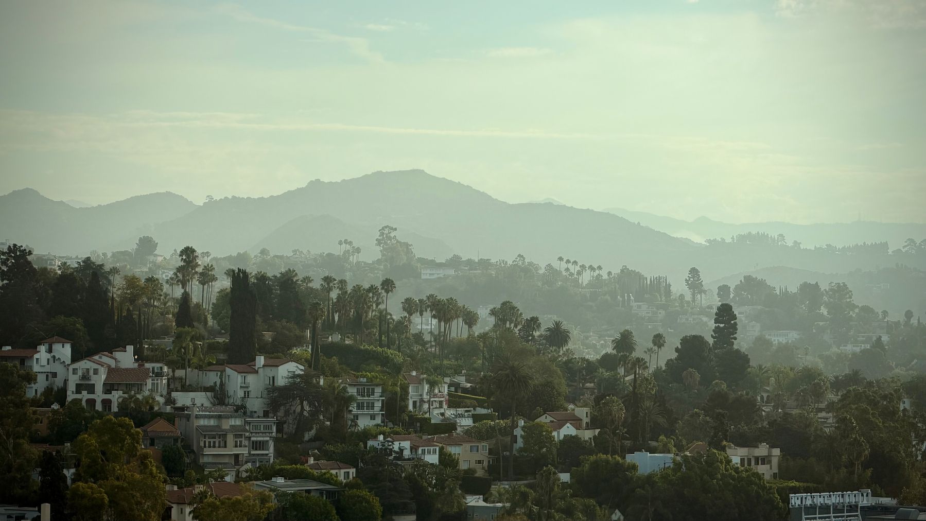 Landscape view of houses on the hills in Hollywood, with the hills in the background covered by a morning haze.