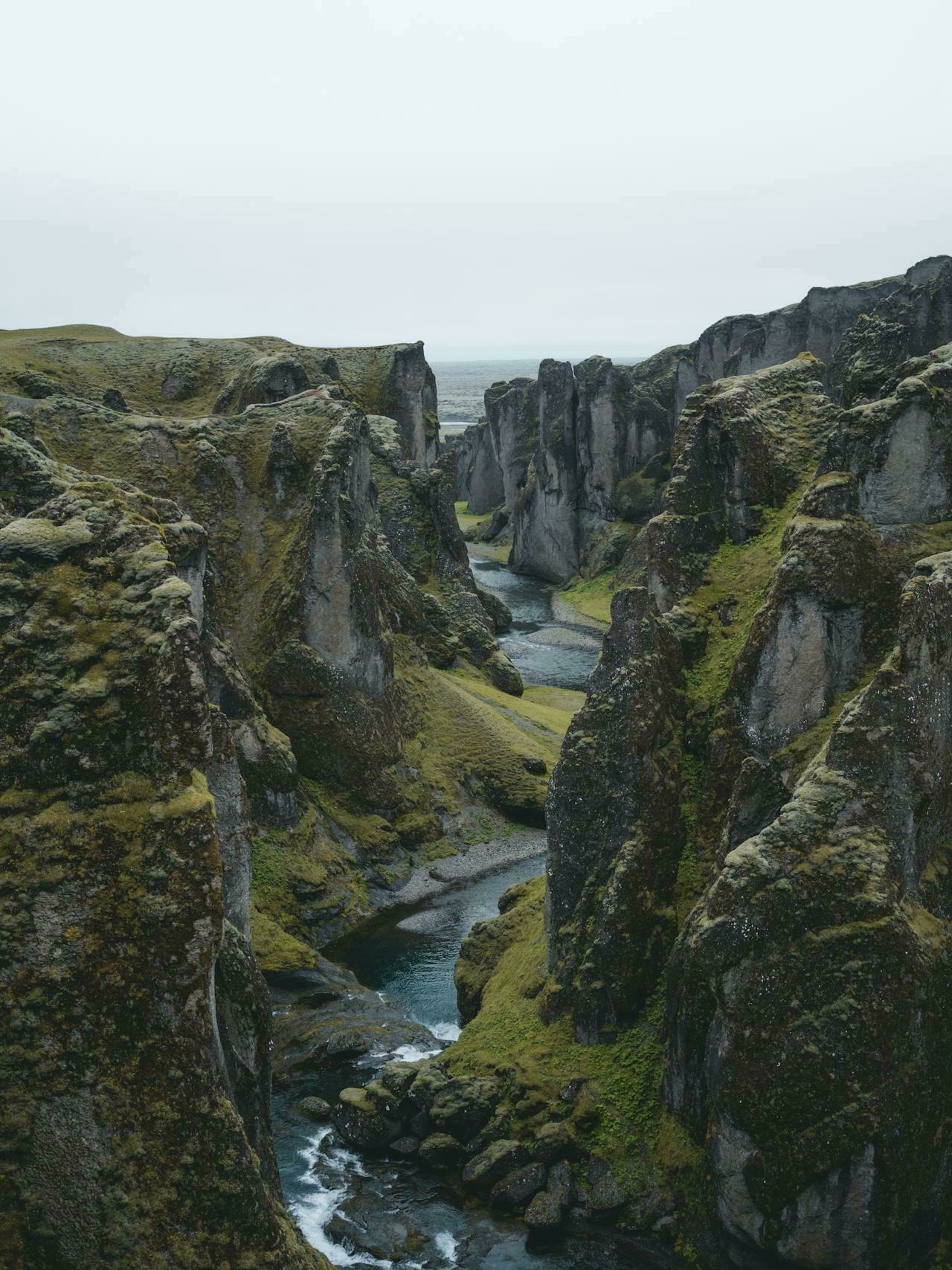 Auto-generated description: A narrow river winds through verdant, steep cliffs in a dramatic canyon landscape.