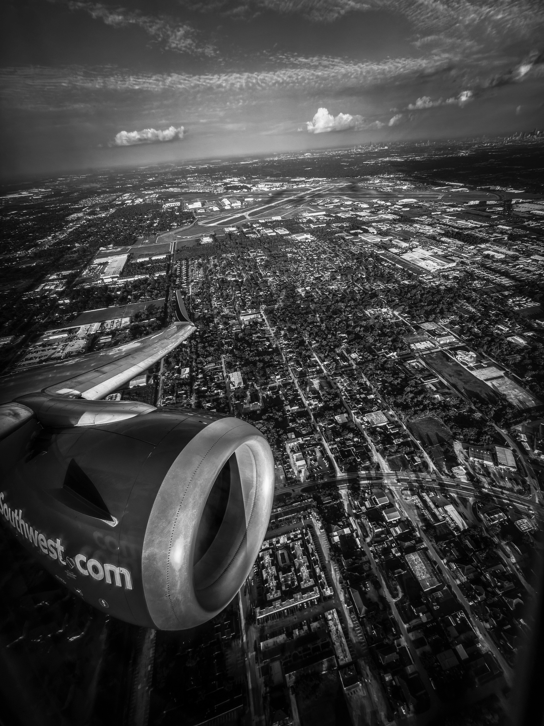 Auto-generated description: An aerial view features a cityscape with a jet engine of a plane visible in the foreground.