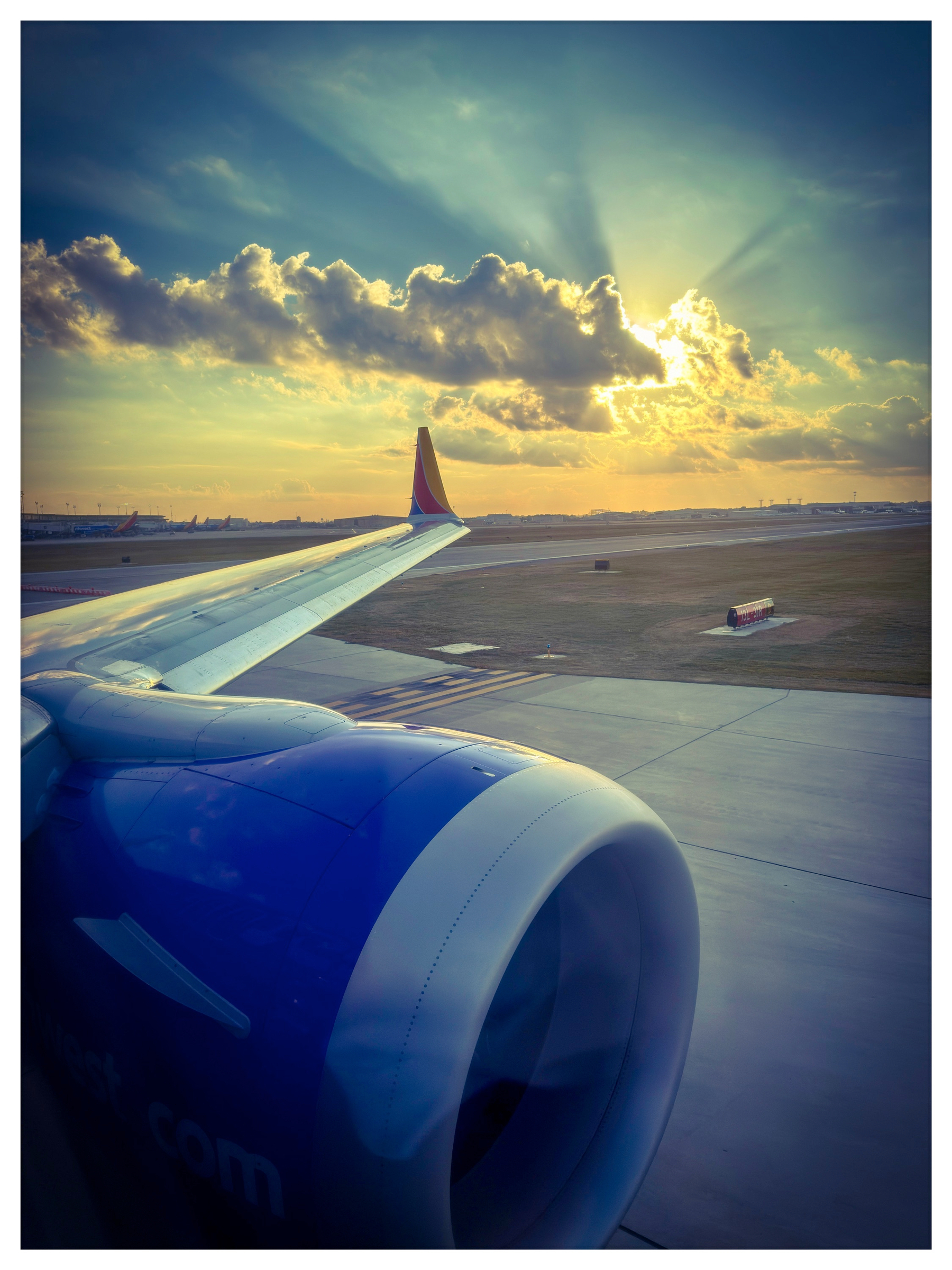 Auto-generated description: An airplane wing and engine are seen from a passenger window with a dramatic sunset and clouds in the background.