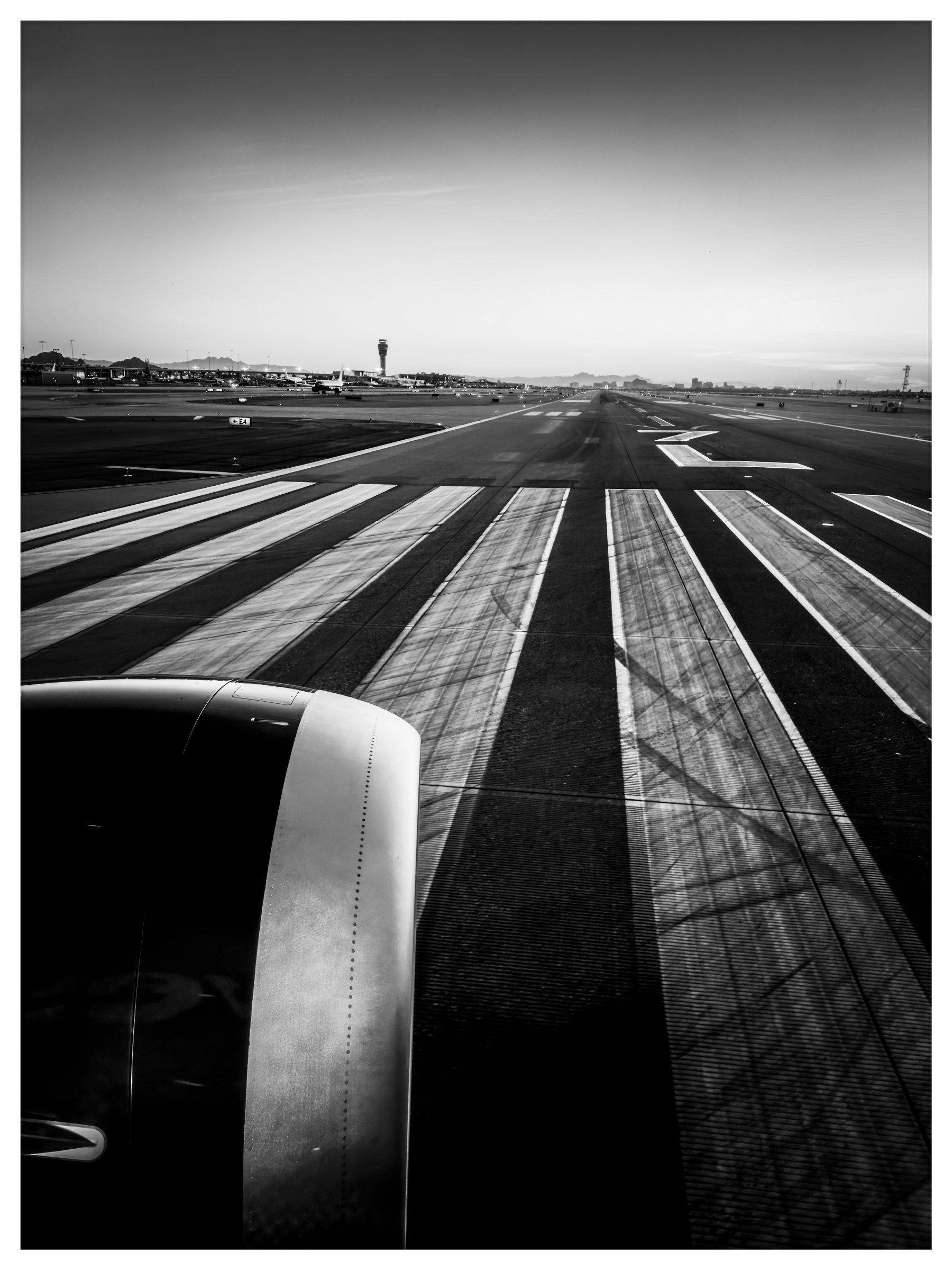 Auto-generated description: An airplane is taxiing on a runway, with the airport control tower visible in the background.