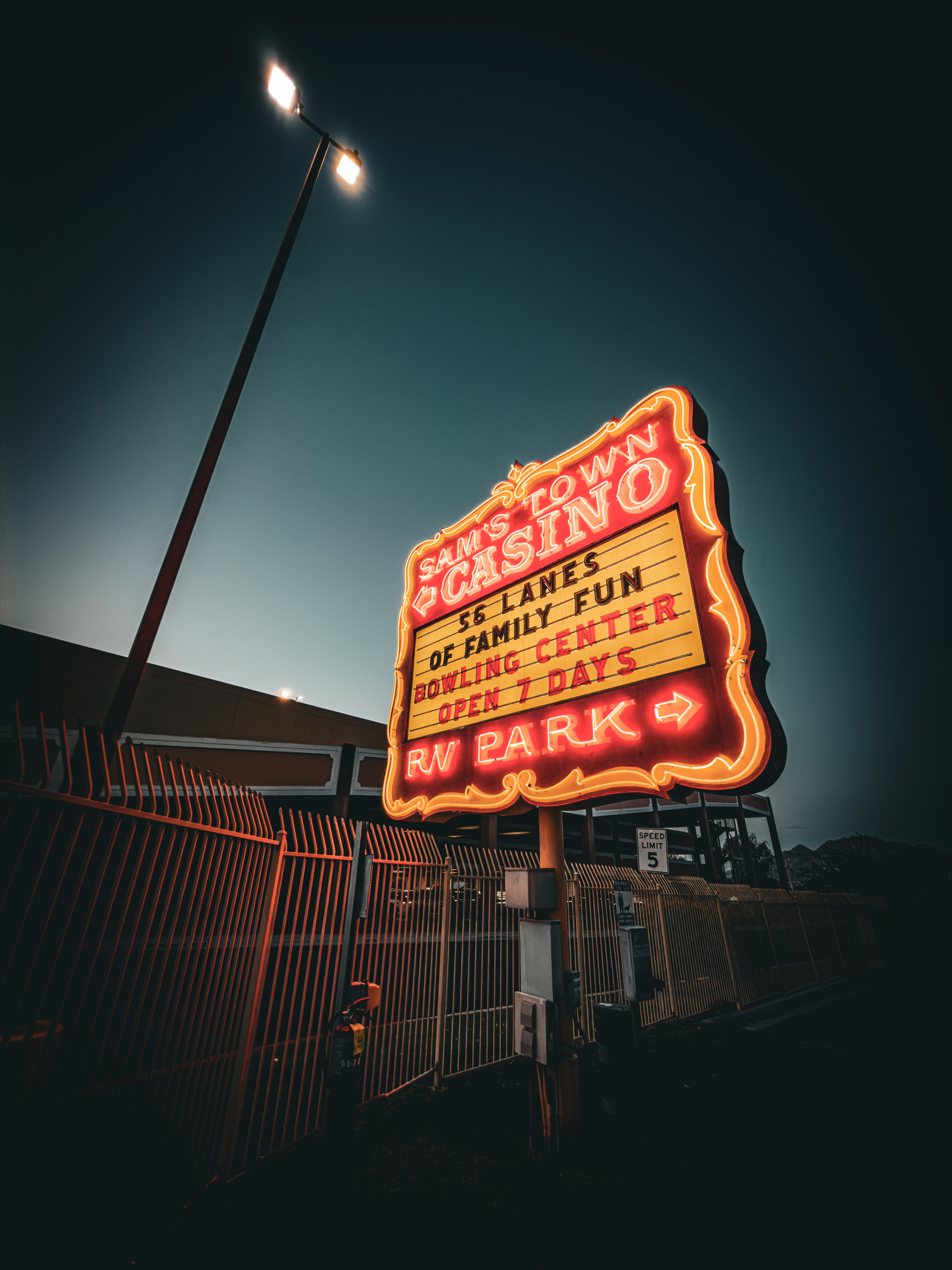 Auto-generated description: A brightly lit neon sign for Sam's Town Casino advertises a bowling center with 56 lanes, family fun, and an RV park, glowing against a dusky sky.