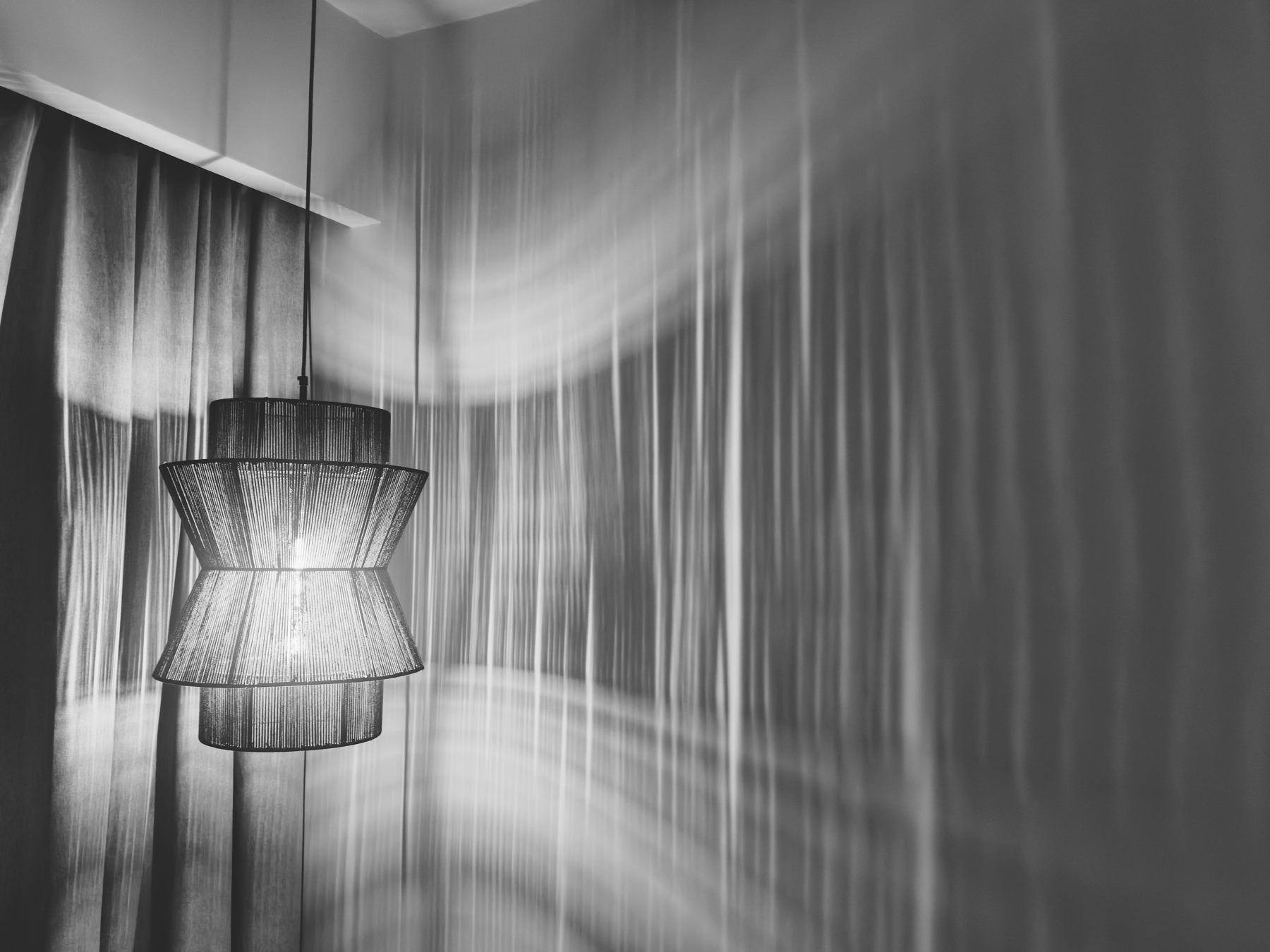 Auto-generated description: A hanging lamp casts intricate shadows on the wall, creating a textured and dynamic lighting effect.