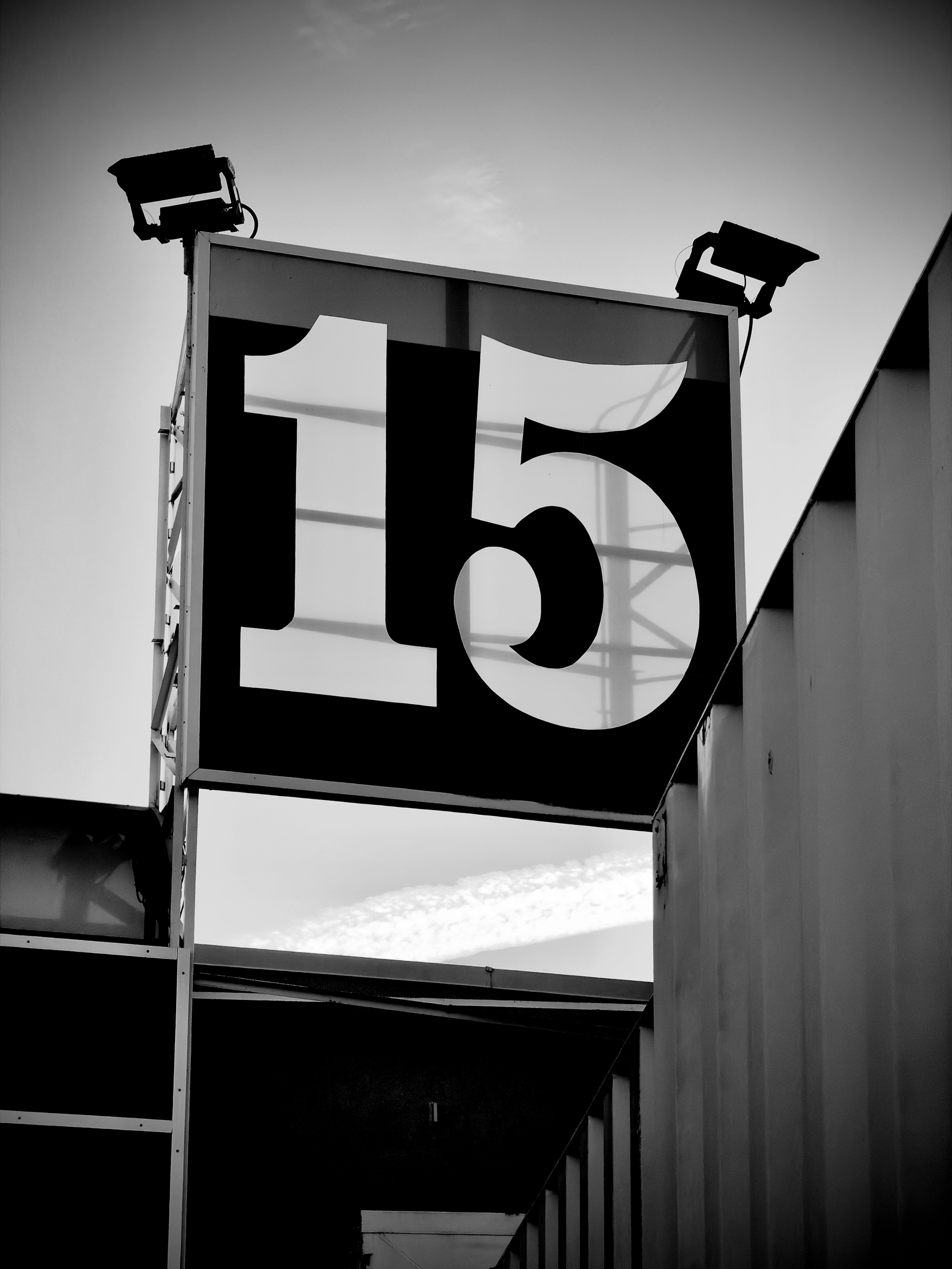 Auto-generated description: A large sign displaying the number 15 is mounted on a metal frame with two spotlights positioned above it.