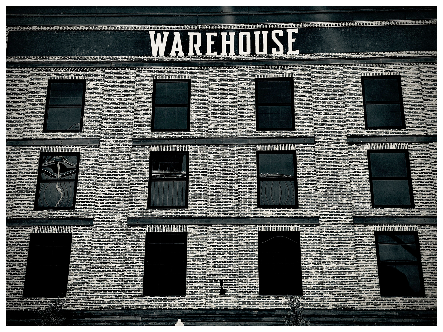 Auto-generated description: A brick building with multiple windows displays the word WAREHOUSE prominently at the top.