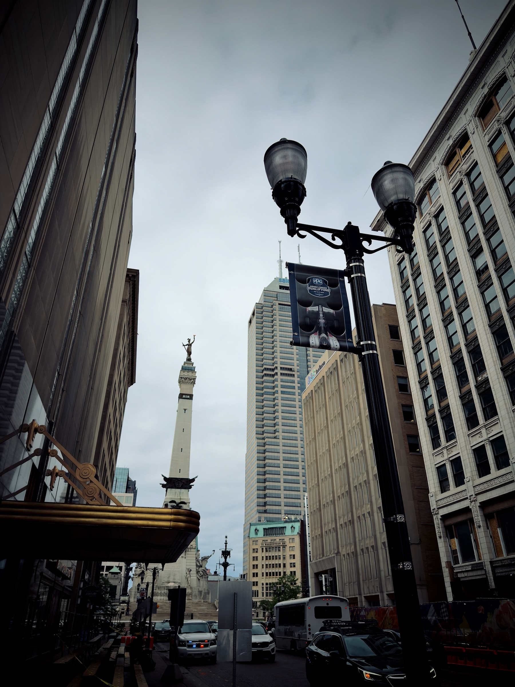 Auto-generated description: A city street view showcases tall buildings framing a prominent monument in the distance, under a cloudy sky.