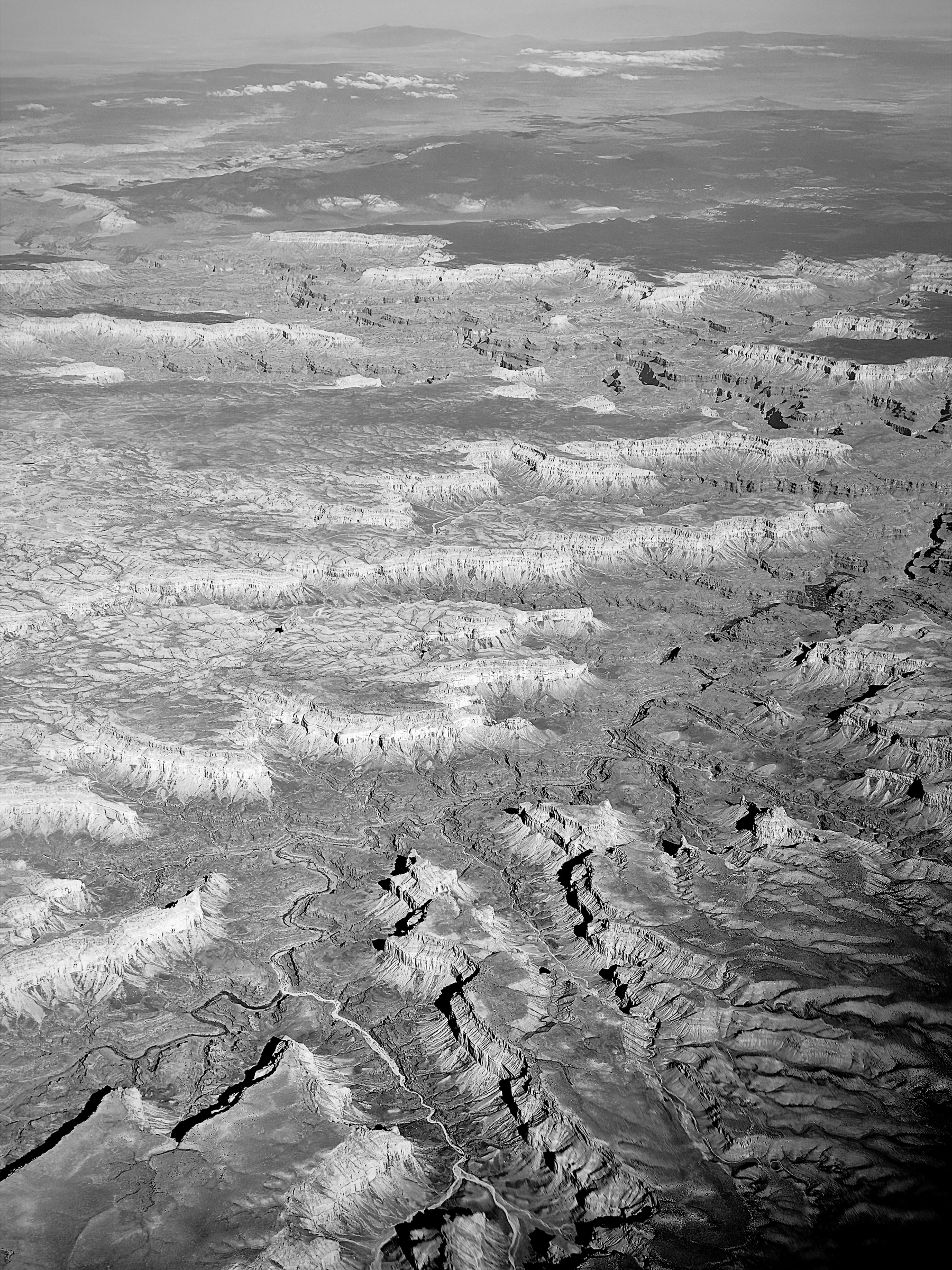 Auto-generated description: A vast and rugged landscape characterized by deep canyons, sharp ridges, and layered rock formations stretches out to the horizon.