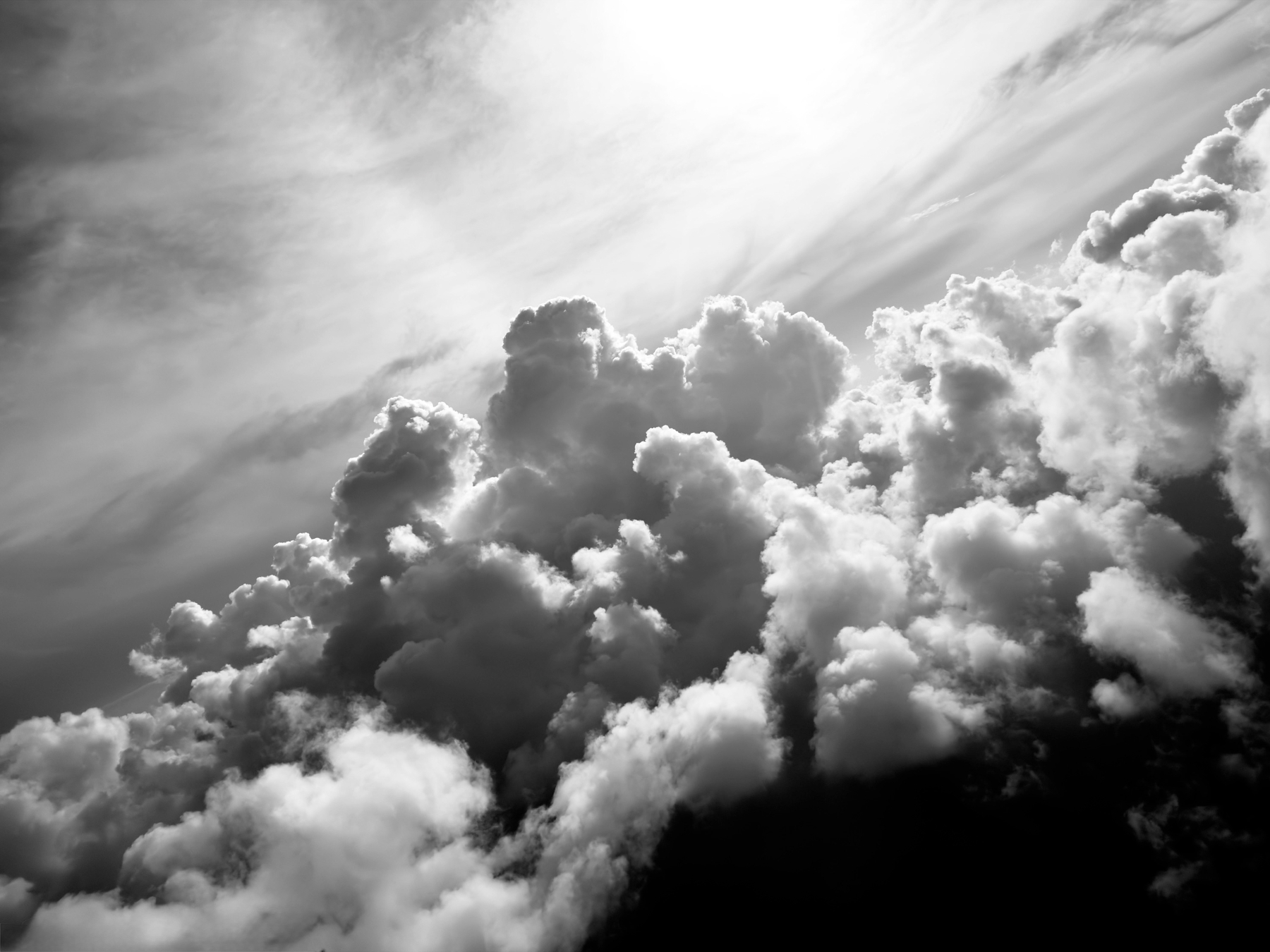Auto-generated description: Dramatic, fluffy clouds fill the sky in a striking black and white scene.