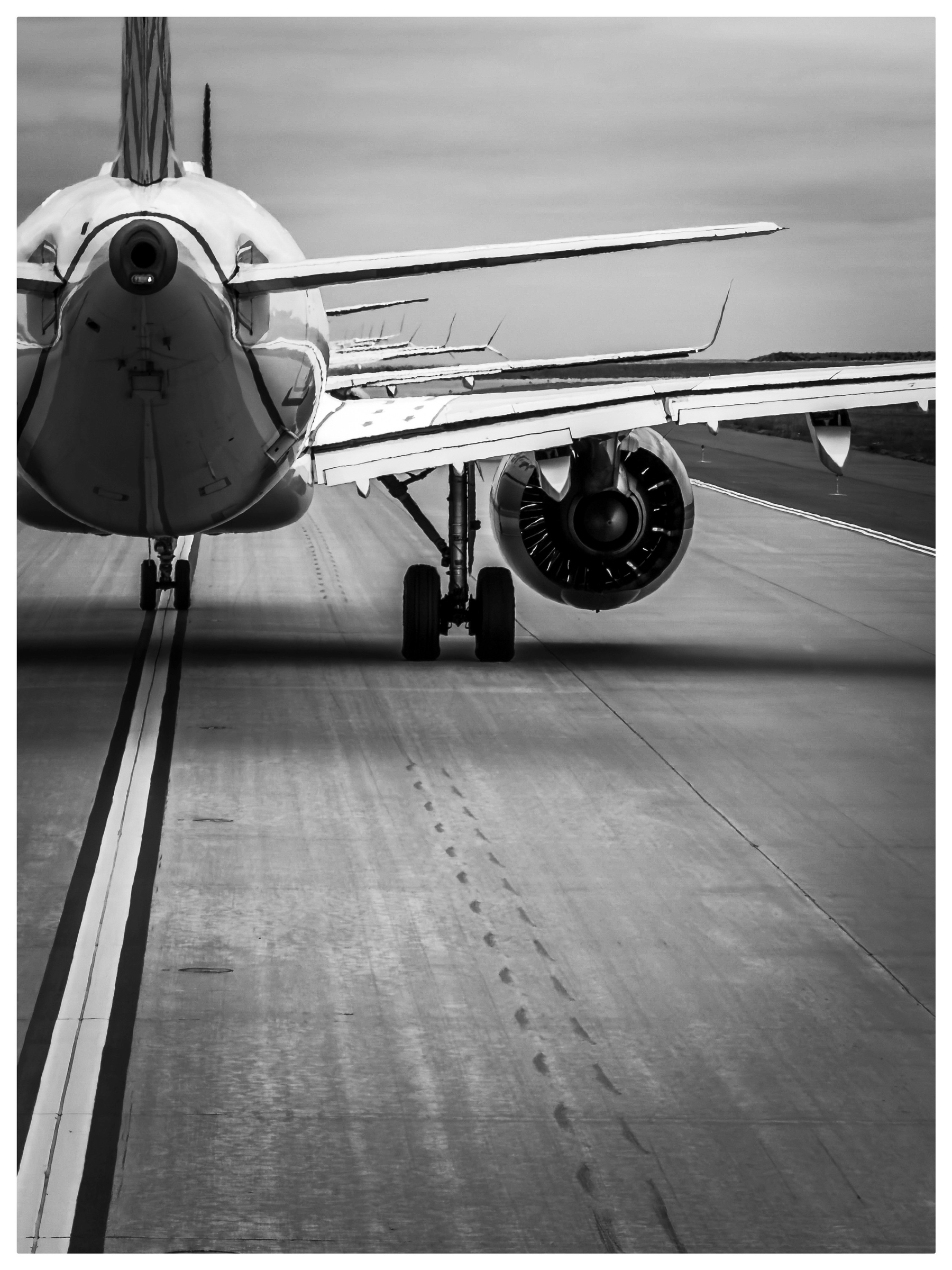 Auto-generated description: A jet airliner is positioned on a runway, viewed from the rear.