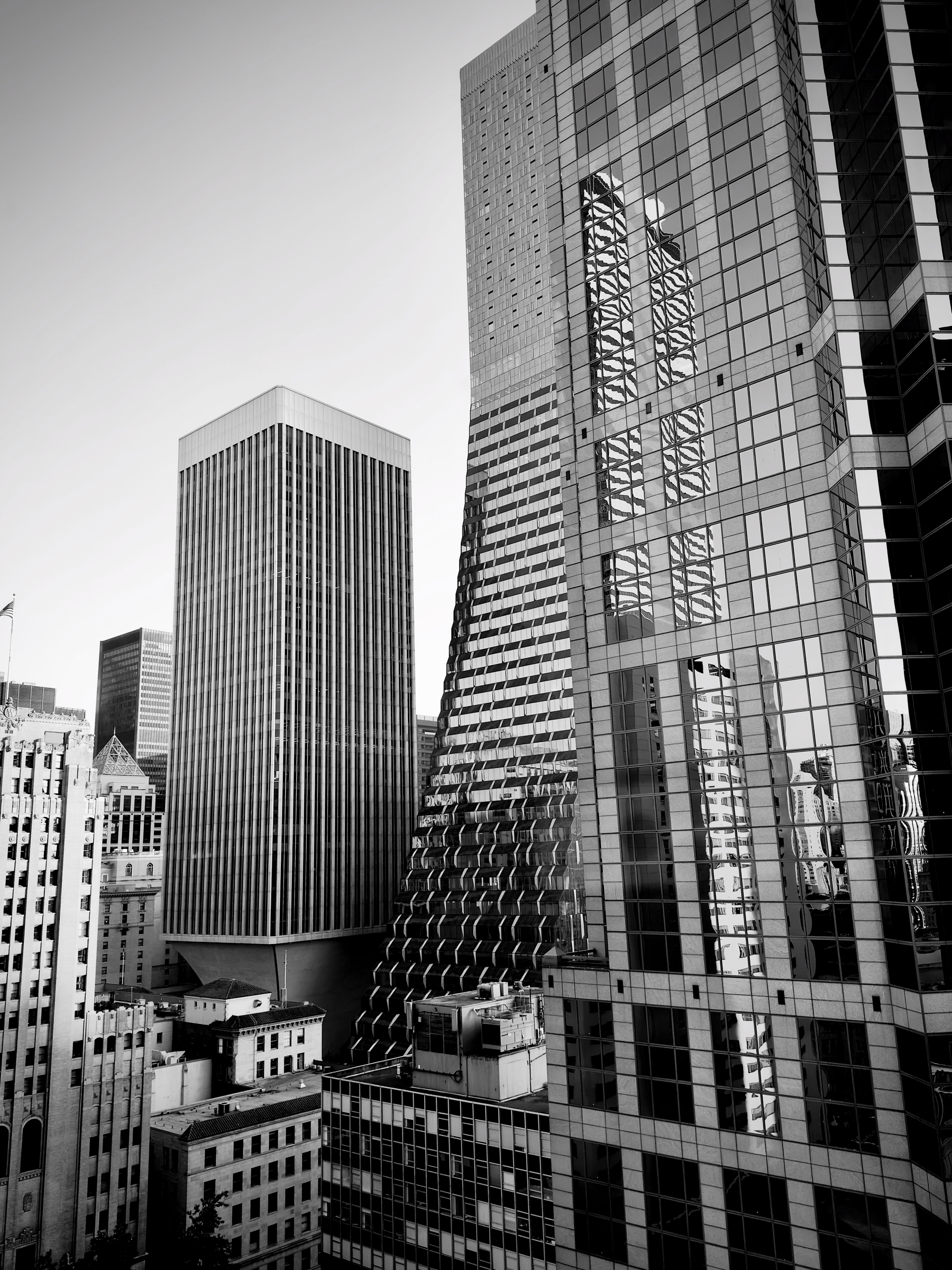 Auto-generated description: A cluster of tall office buildings with reflective glass windows is captured in a black and white photograph.