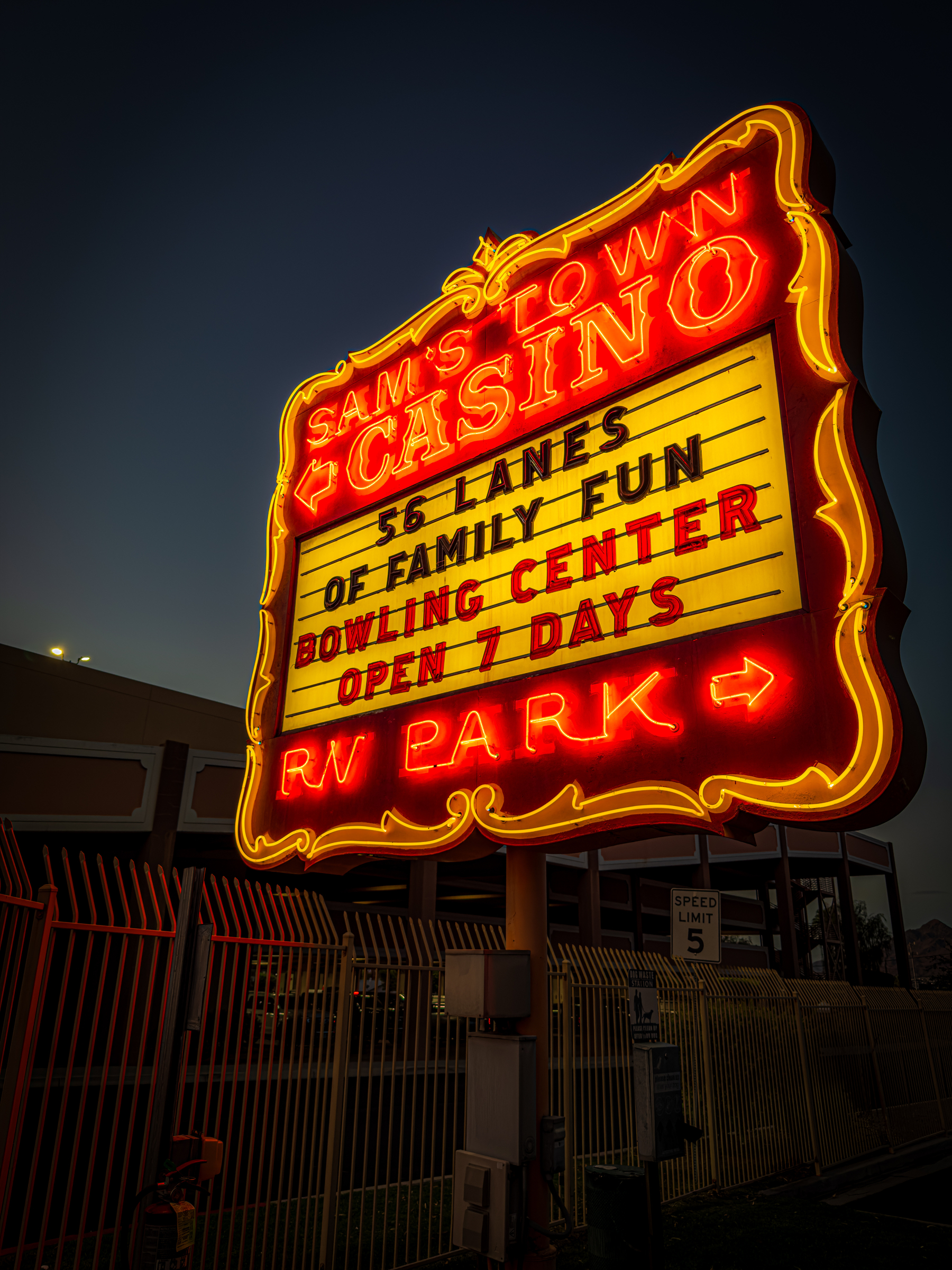 Auto-generated description: A brightly lit neon sign advertises Sam's Town Casino, highlighting 56 lanes of family fun at a bowling center open seven days a week with an RV park.