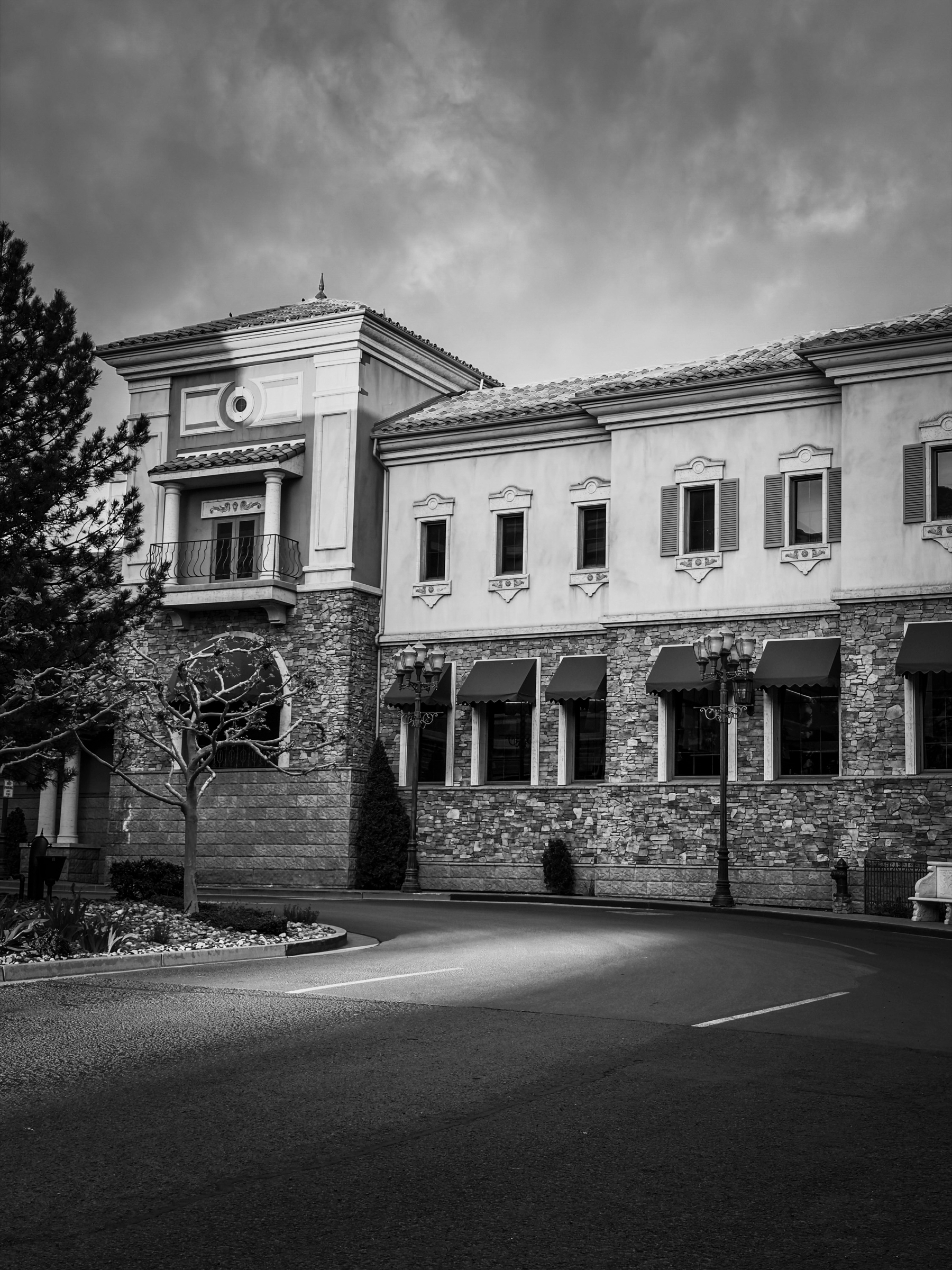 Auto-generated description: A grand building with stone and stucco facade stands against a cloudy sky, featuring arched windows and decorative elements.