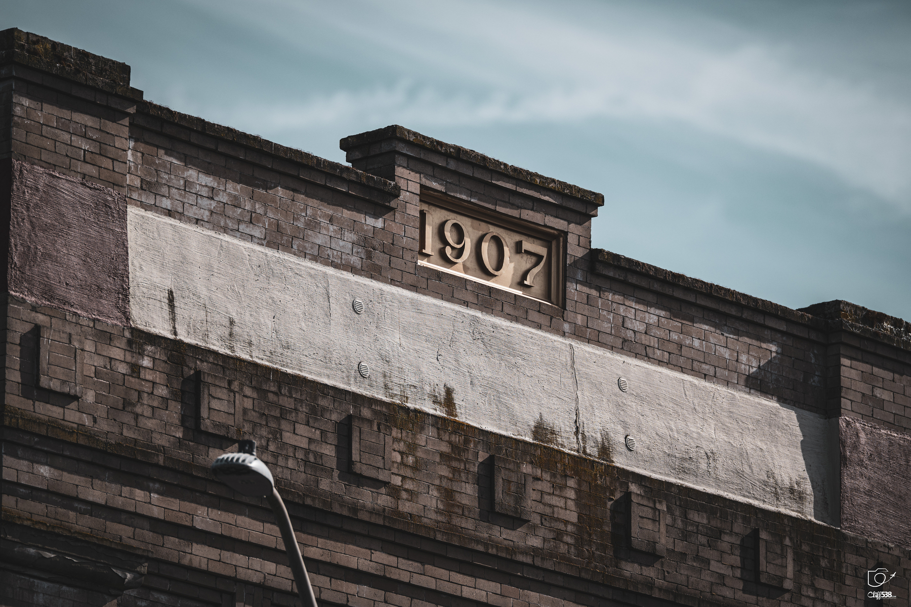 Auto-generated description: A brick building facade features the year 1907 prominently displayed at the top.