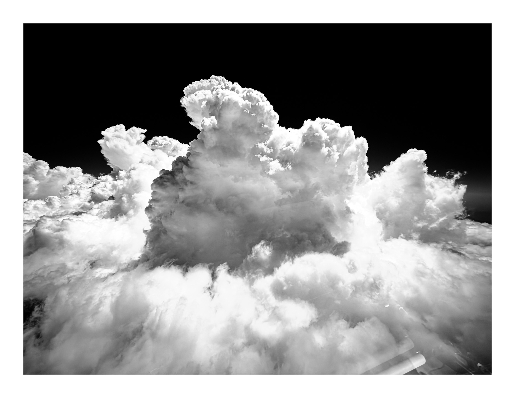 Auto-generated description: A large, dense cloud formation rises dramatically against a dark sky.