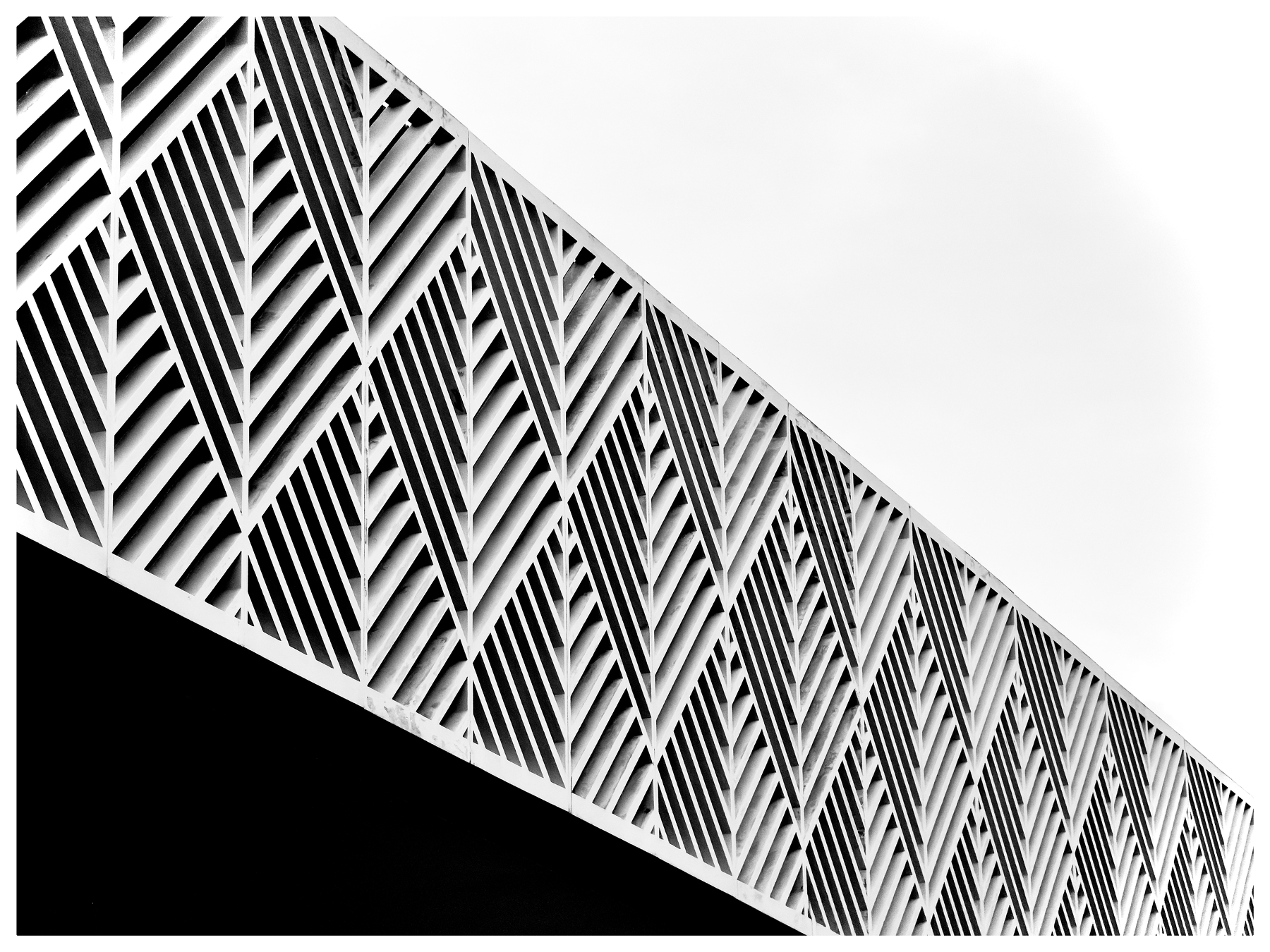 A detailed architectural facade features a pattern of diagonal, crisscrossing lines creating a geometric design.