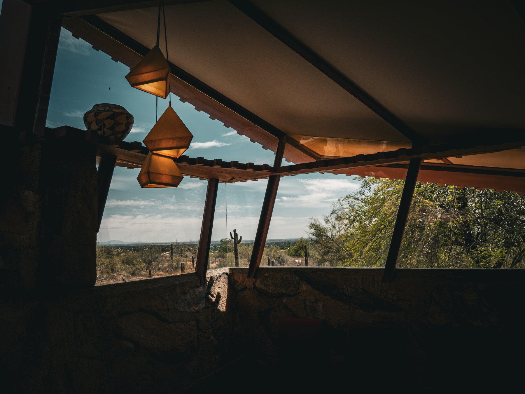 Auto-generated description: A dimly lit room with angular windows offers a view of a desert landscape outside.