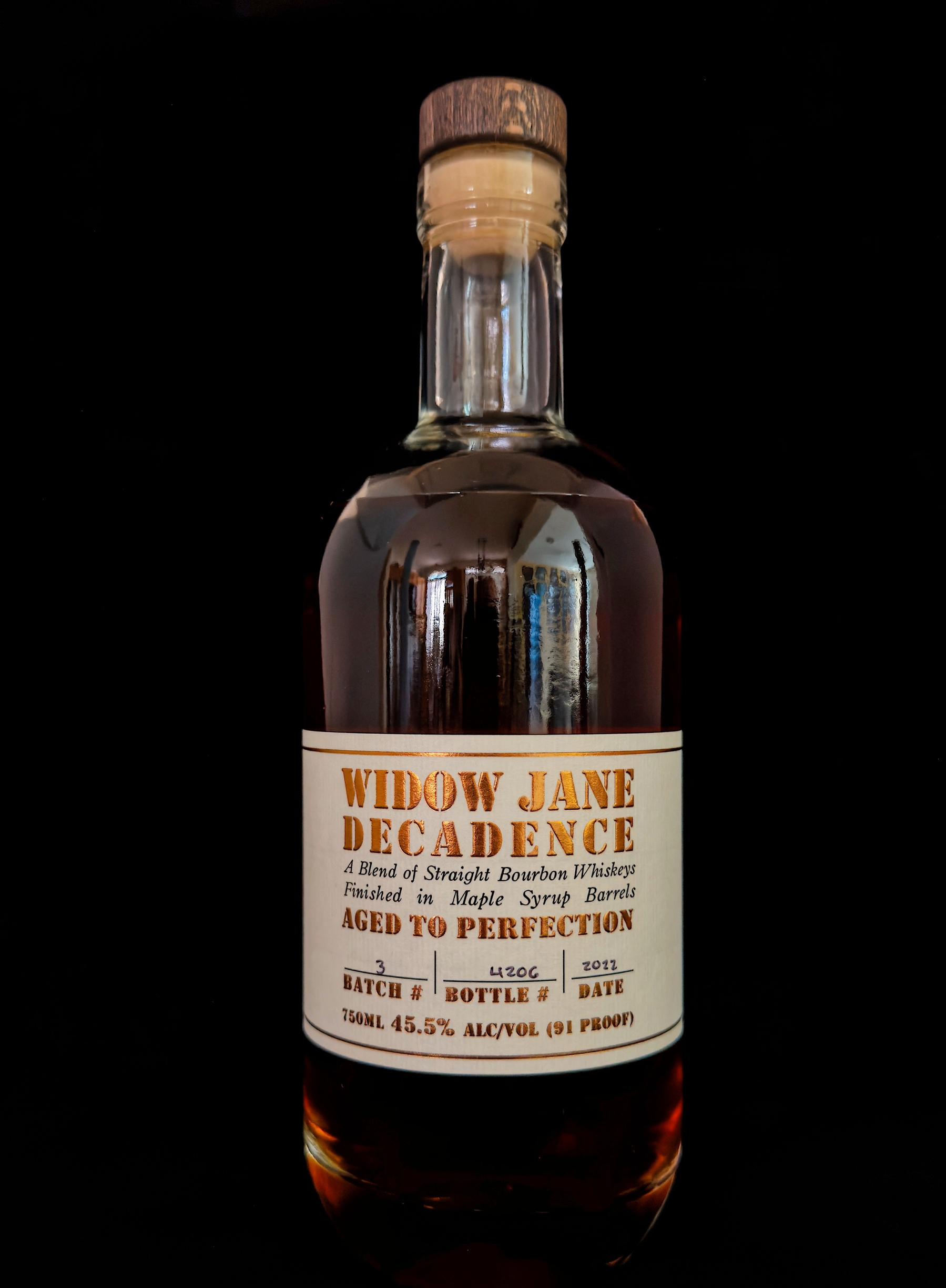 Auto-generated description: A bottle of Widow Jane Decadence bourbon whiskey is displayed against a black background, highlighting its label that mentions aging in maple syrup barrels.