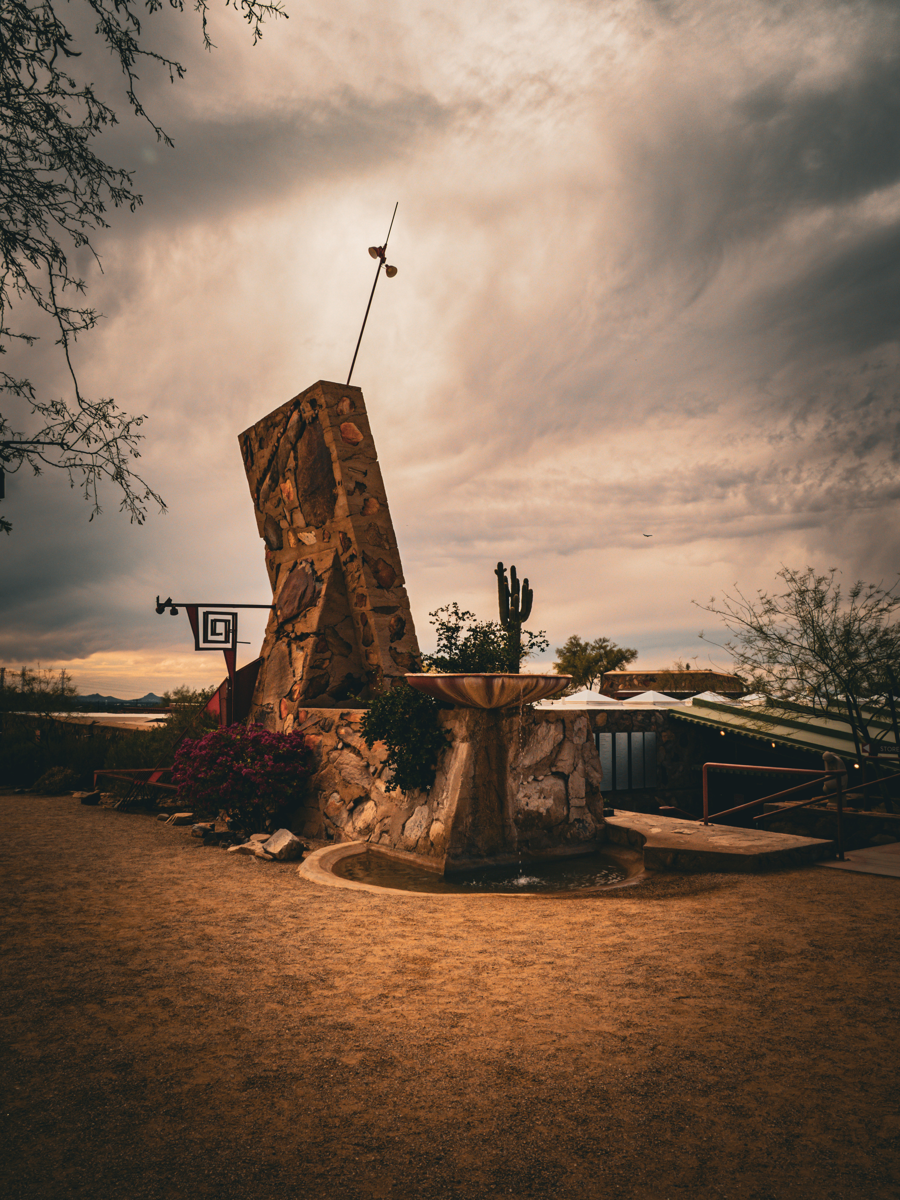 Auto-generated description: A uniquely designed stone sundial stands amidst a desert landscape with a cloudy sky.