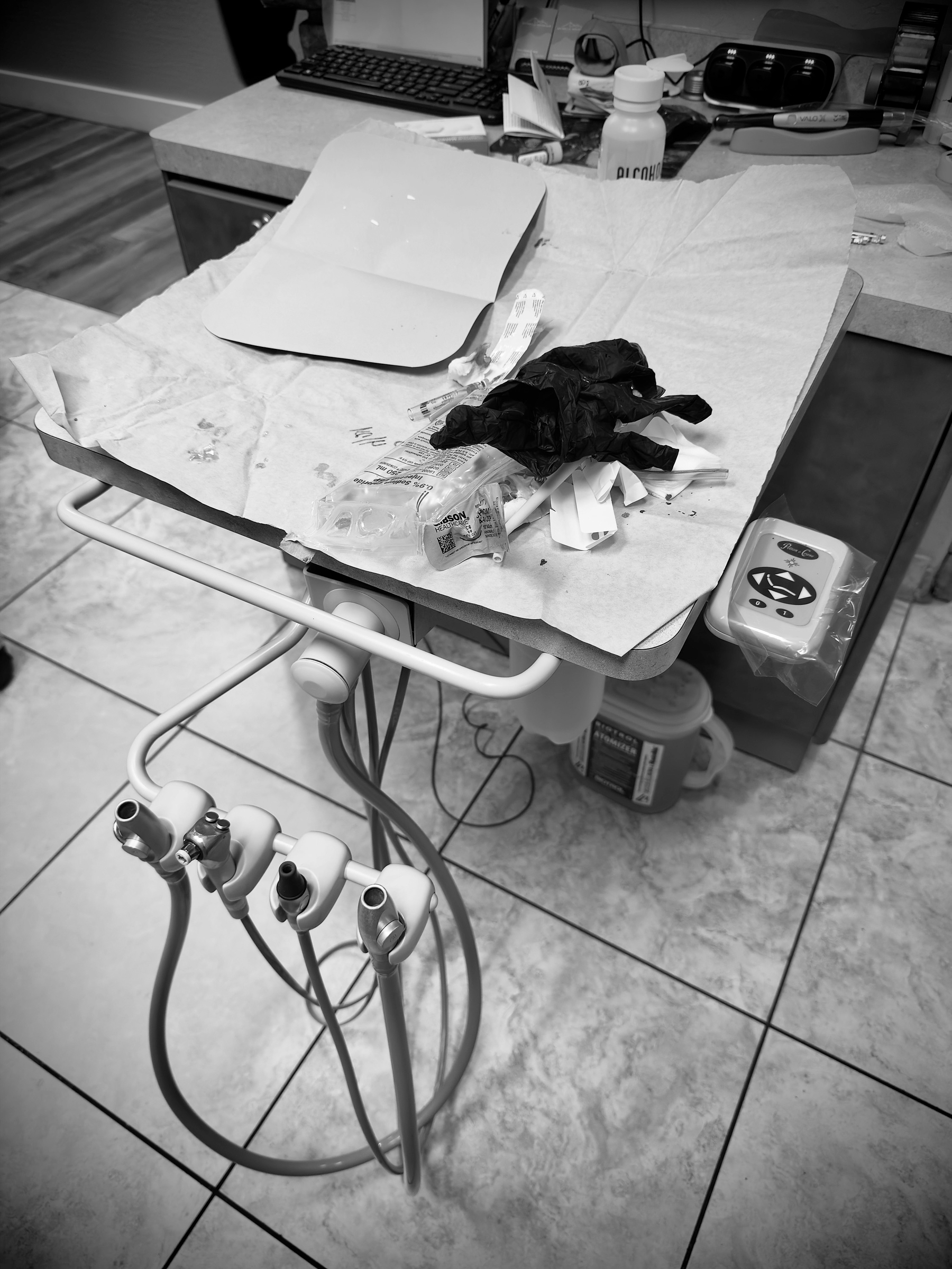 Auto-generated description: A dental workstation is cluttered with paper, tools, and a pair of gloves next to a dental instrument holder.