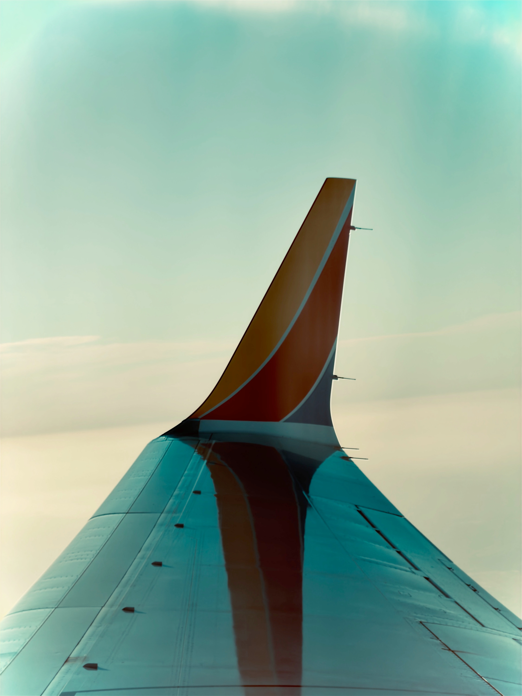Auto-generated description: An airplane wing with a colorful winglet is seen against a clear sky.