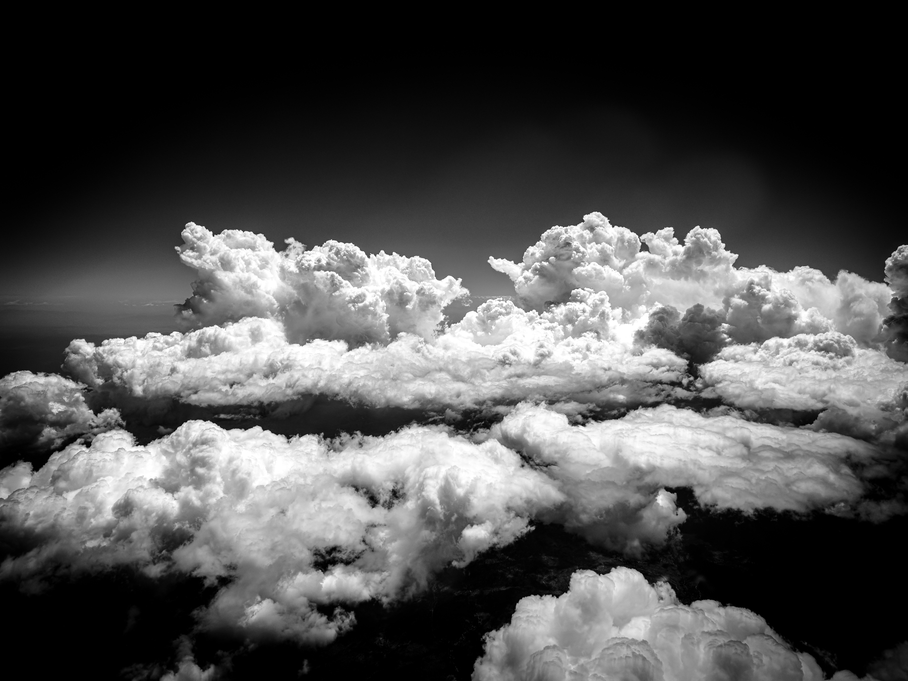 Auto-generated description: Billowing clouds stretch across the sky with varying textures and depths, creating a dramatic and dynamic scene.