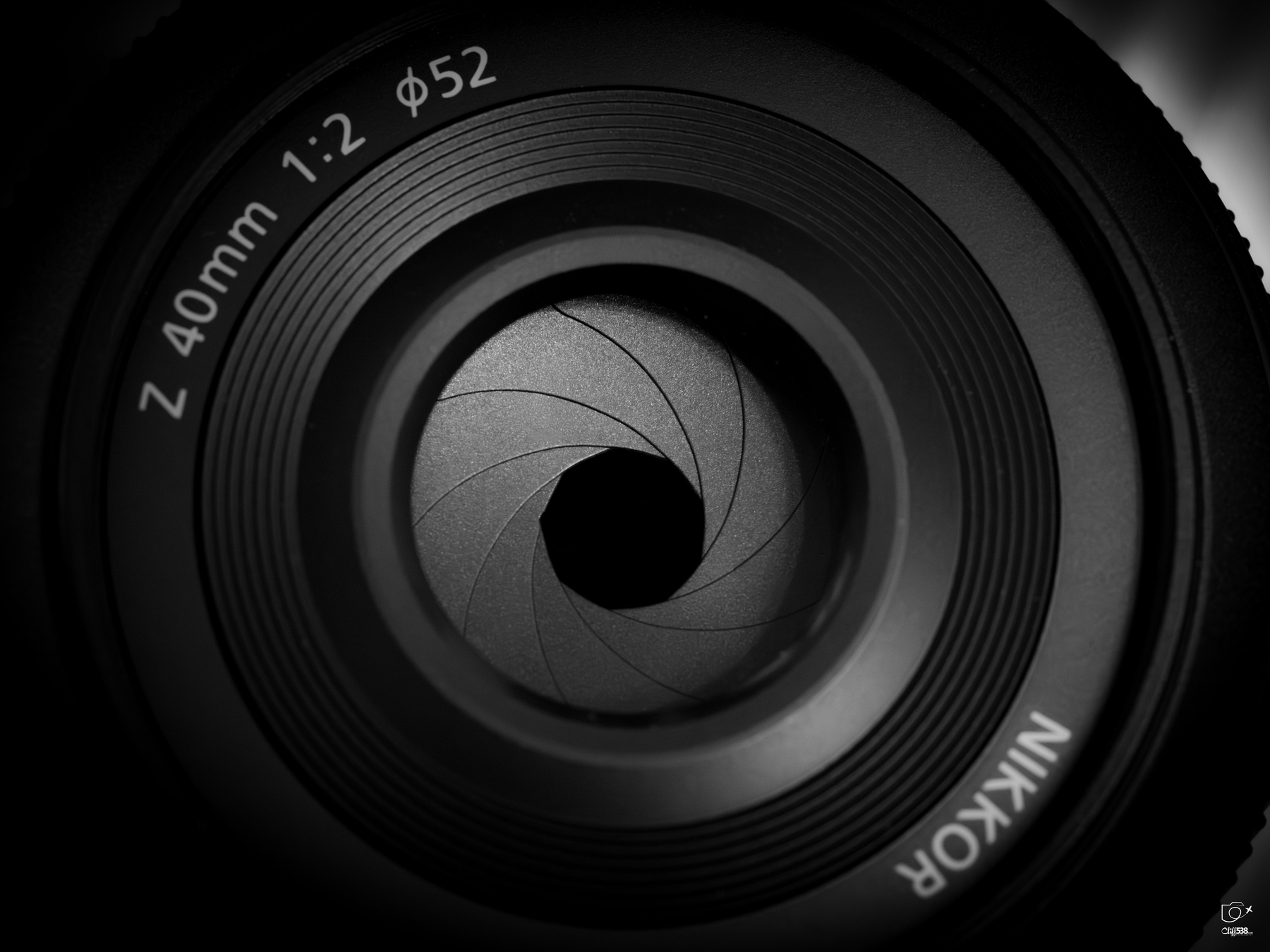 Auto-generated description: A close-up view of a camera lens aperture is shown with visible aperture blades and text indicating specifications.