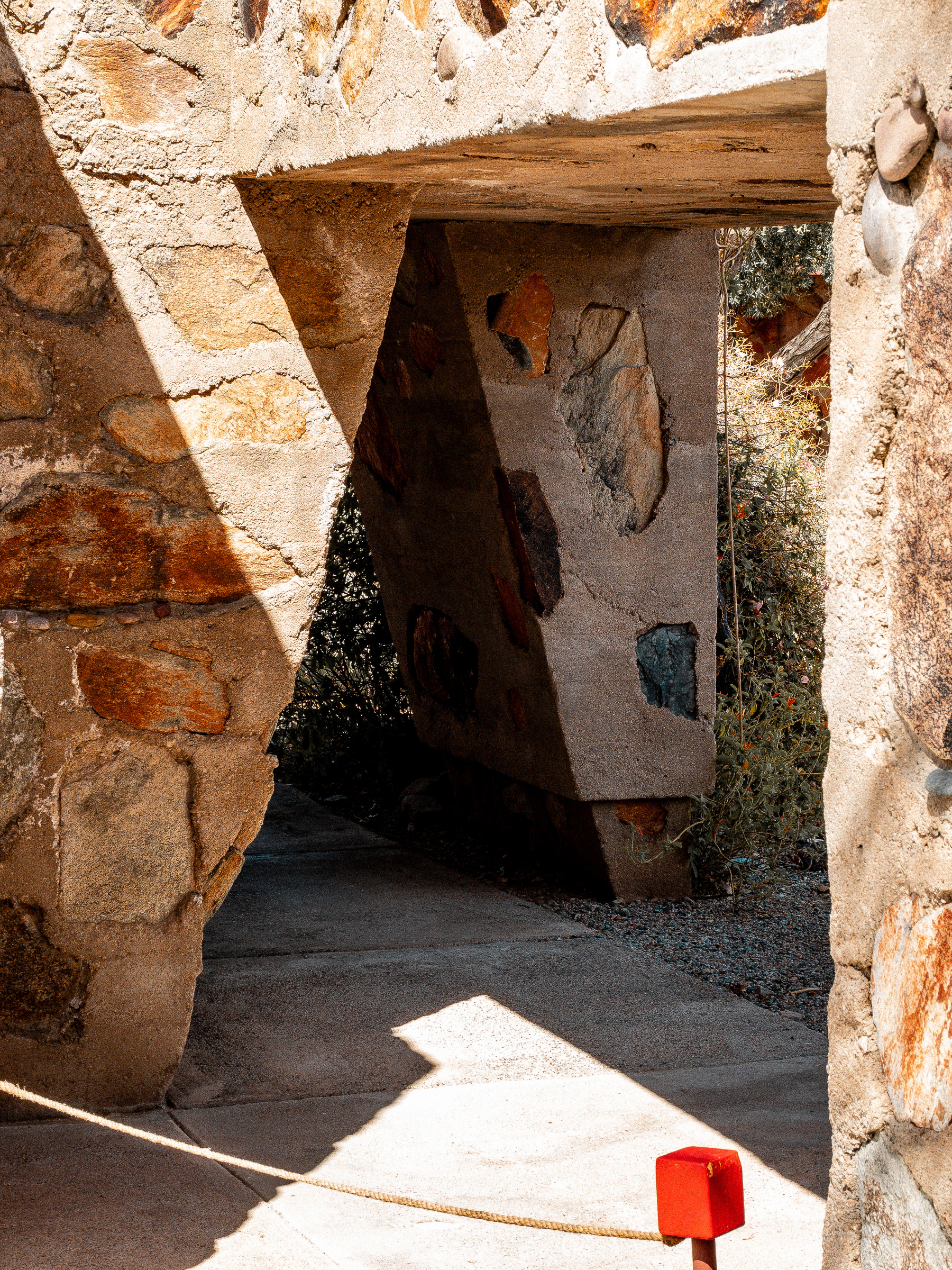 Auto-generated description: A stone and concrete architectural structure with angular lines and a red barrier in the foreground is illuminated by sunlight.