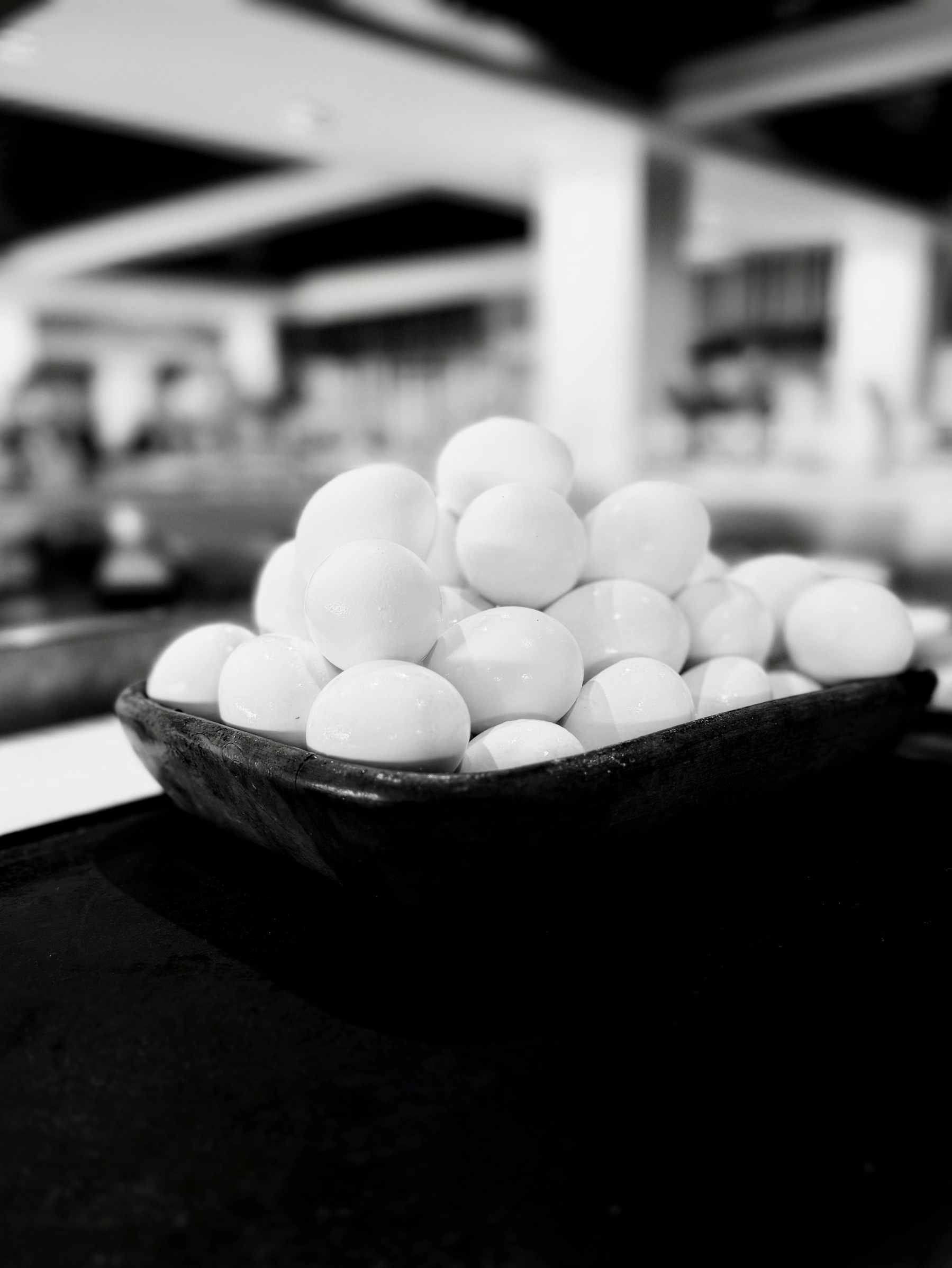 Auto-generated description: A rectangular tray holds a large stack of eggs in a monochromatic setting.