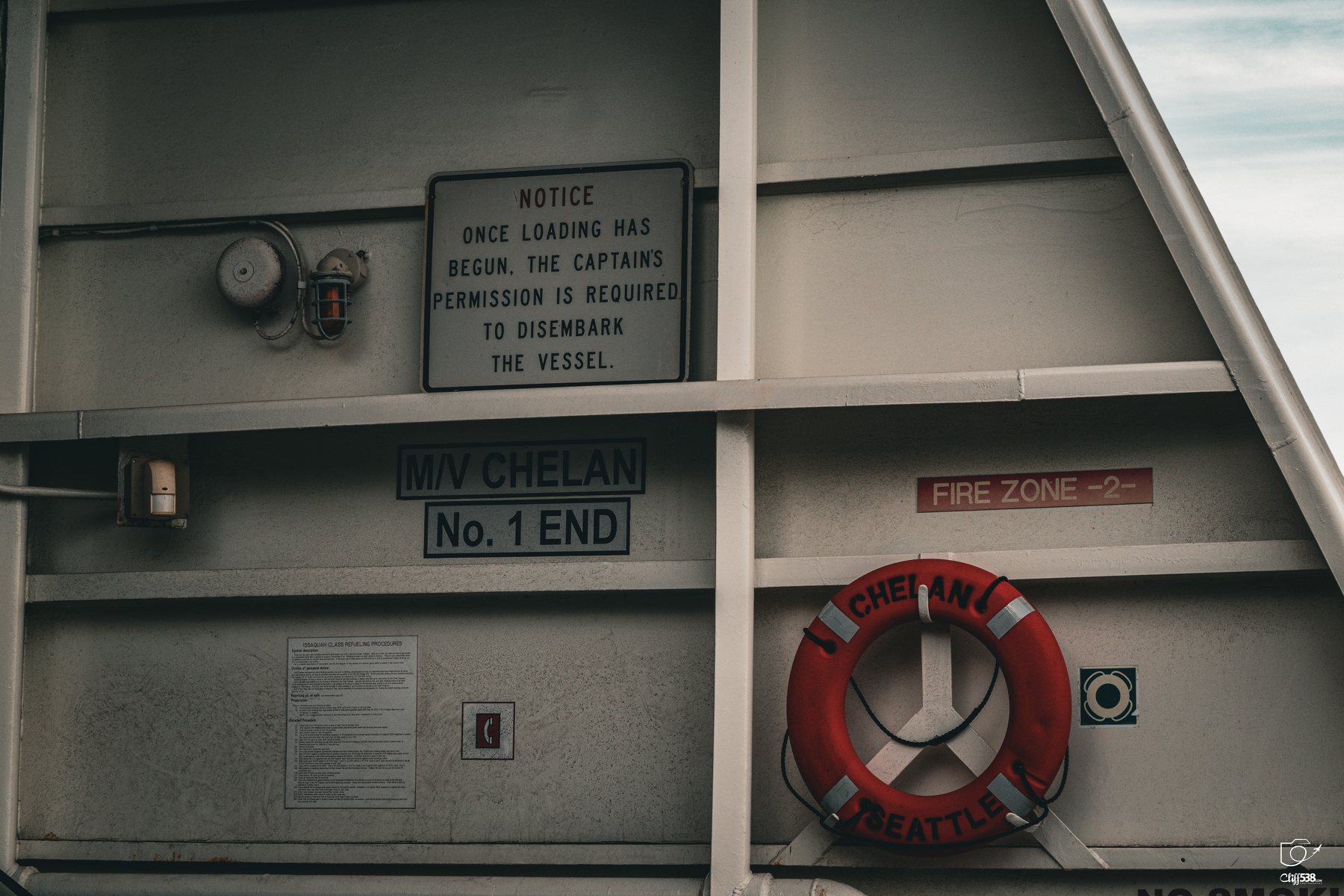 Auto-generated description: A section of a vessel named MV Chelan displays safety signs, a life preserver, and instructions regarding permission needed to disembark.