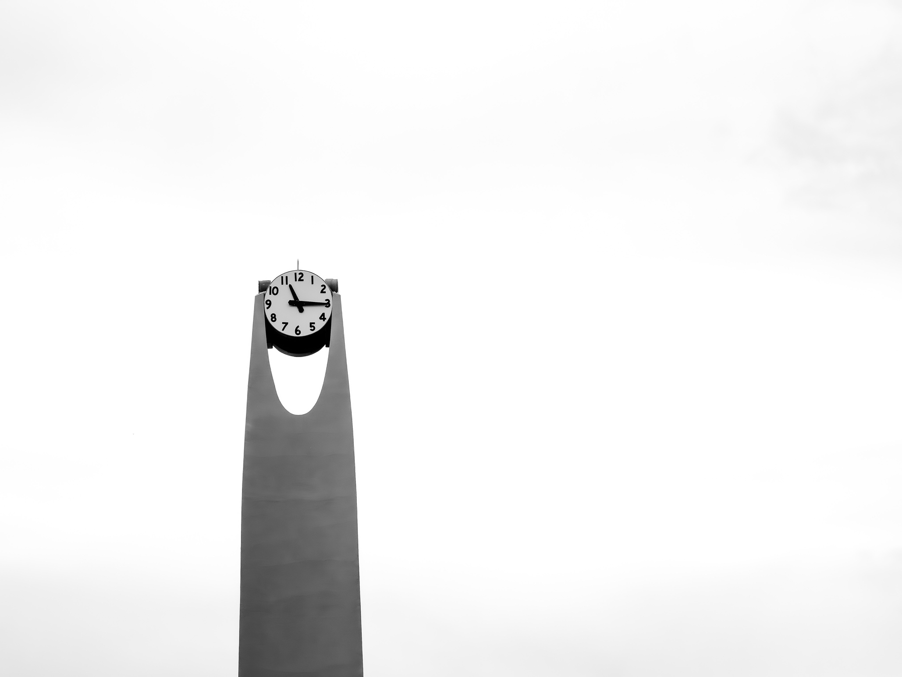 Auto-generated description: A minimalistic clock tower is set against a cloudy sky.