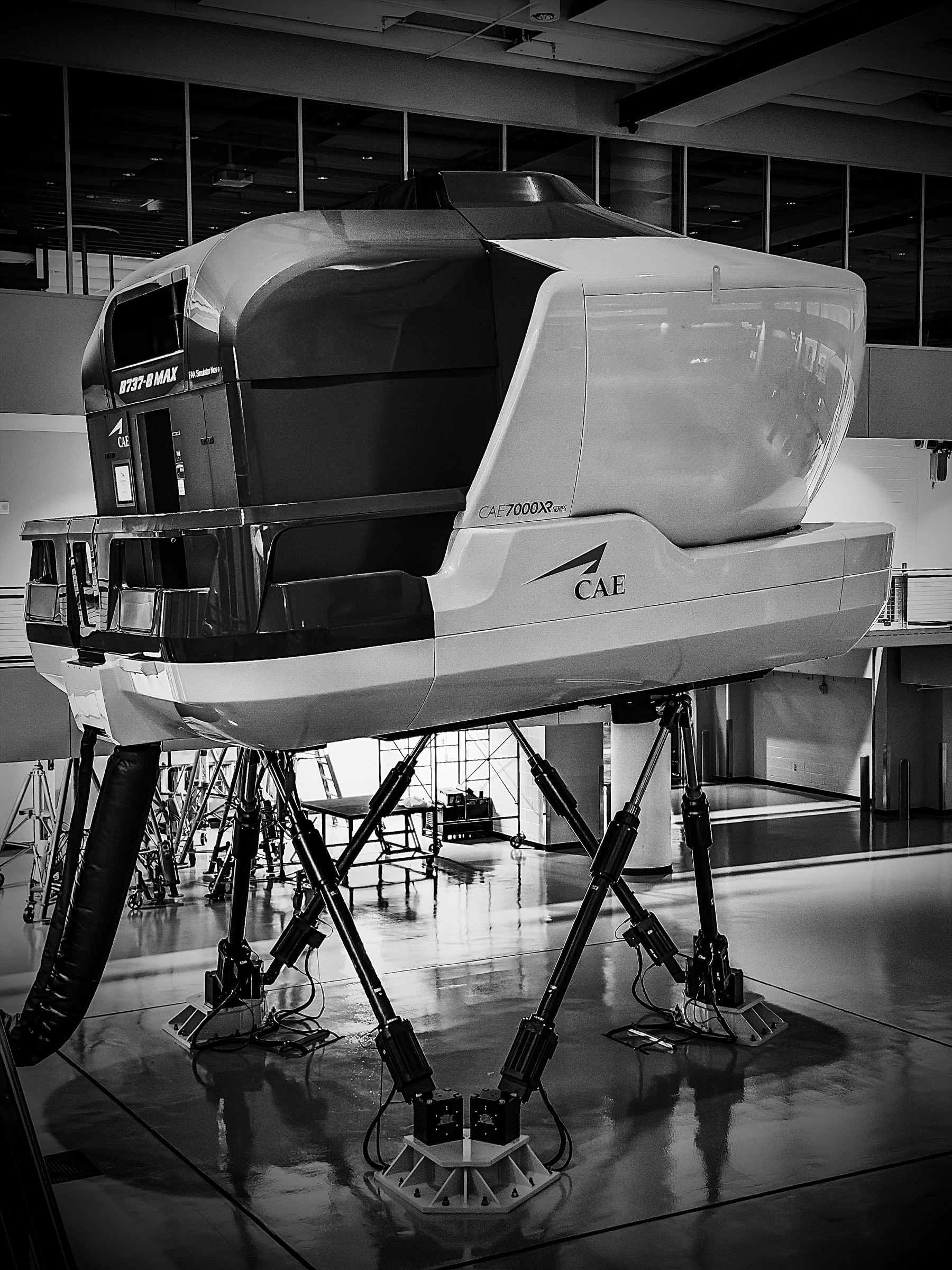 Auto-generated description: A flight simulator resembling the cockpit of an aircraft is mounted on a platform with hydraulic legs.