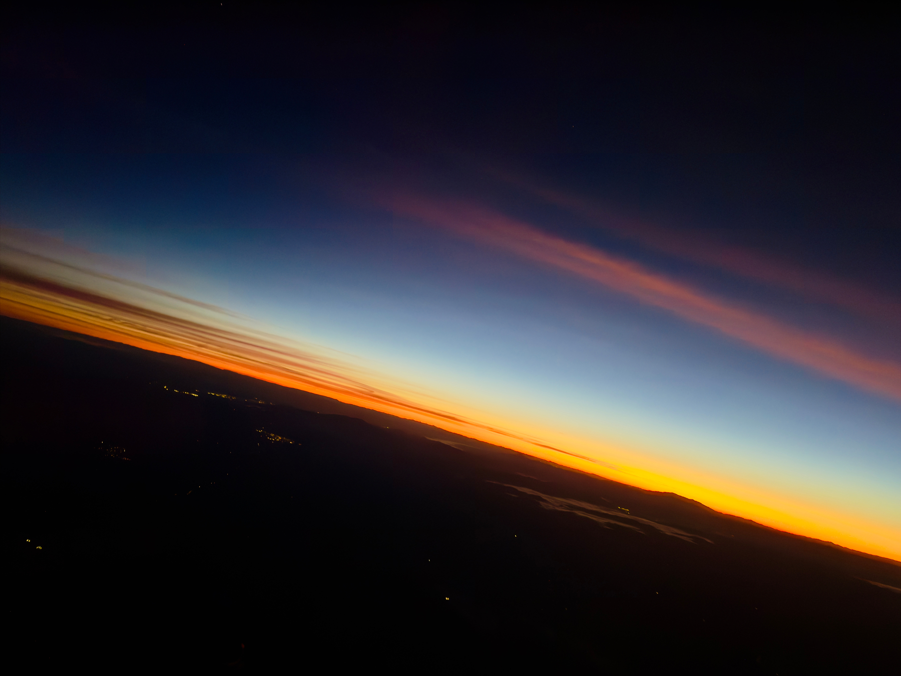 A vivid gradient sky transitions from deep blue to vibrant orange over a silhouetted landscape at sunset or sunrise.