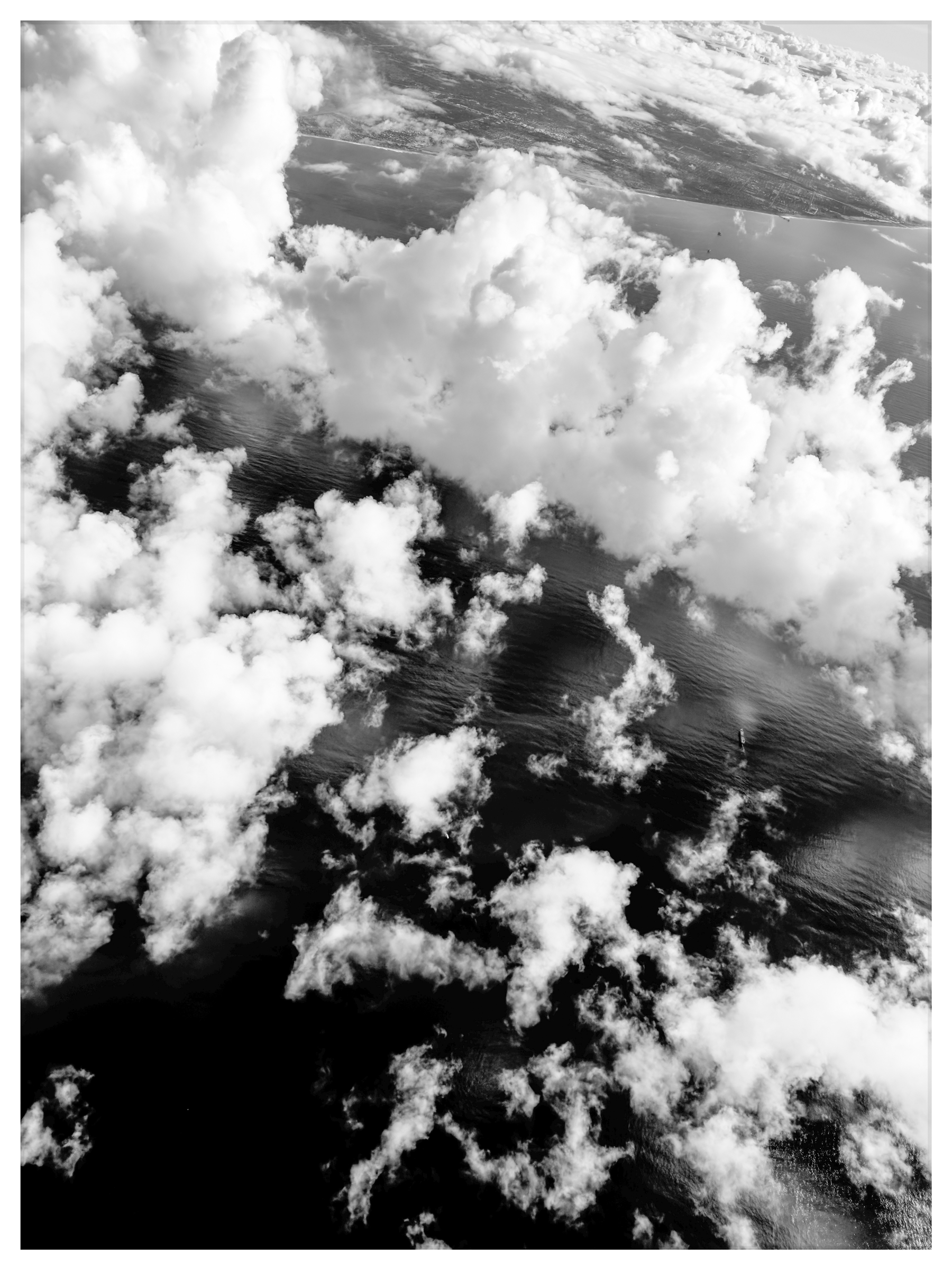 Auto-generated description: Clouds are scattered across a vast expanse of water, creating a dynamic aerial view.