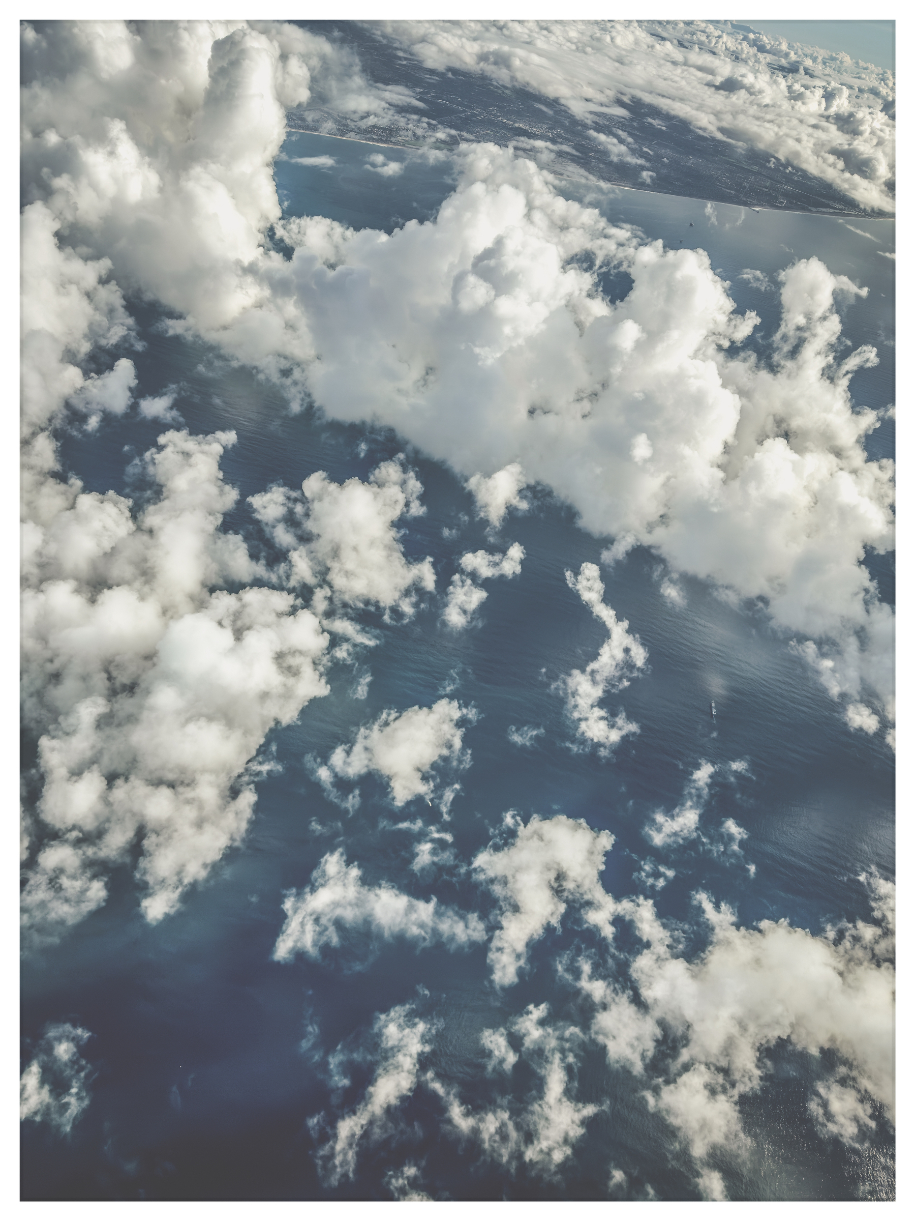 Auto-generated description: An aerial view of fluffy white clouds scattered above a vast ocean surface.