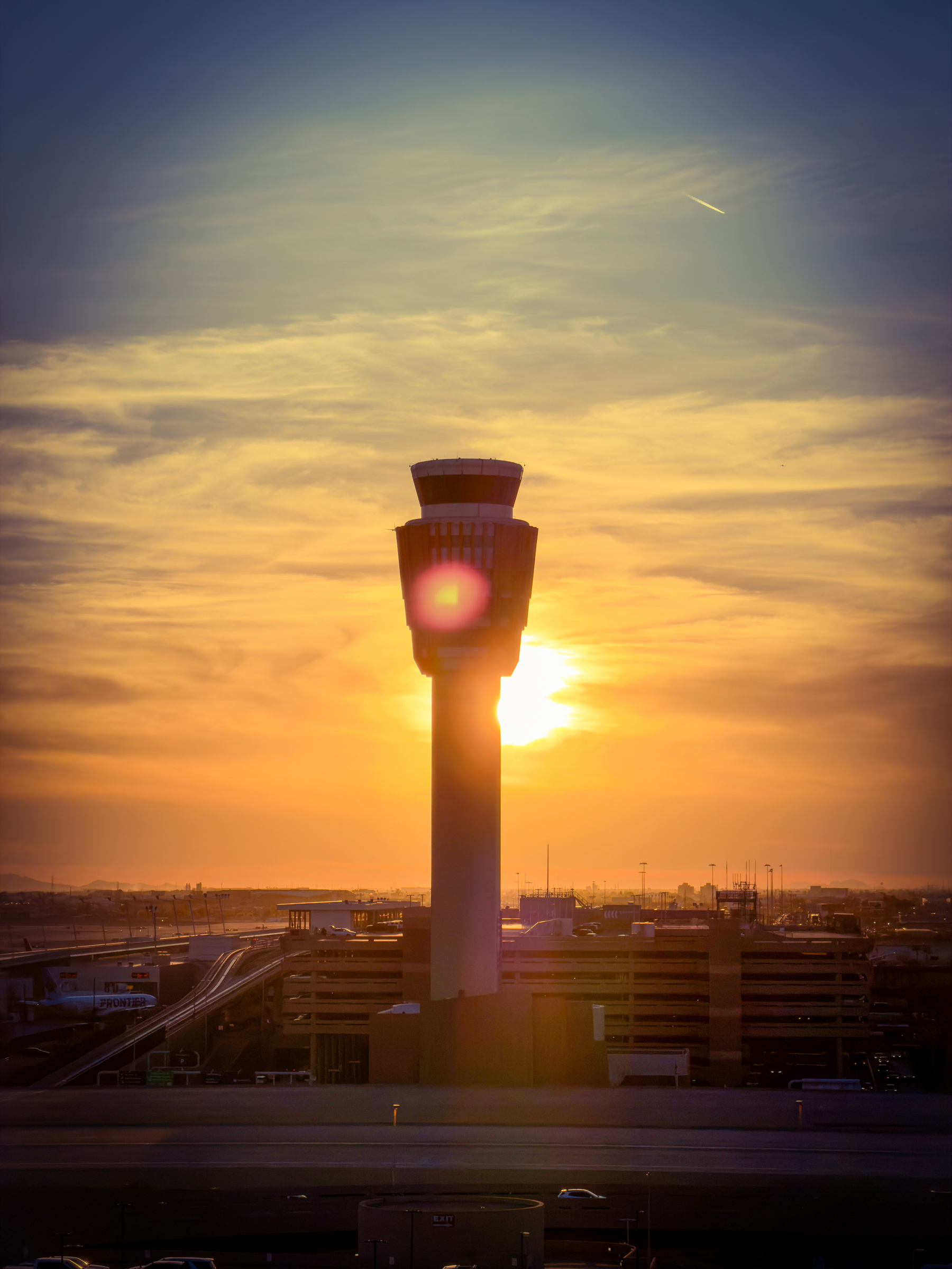 Auto-generated description: A control tower stands silhouetted against a vibrant sunset, with warm hues illuminating the sky.