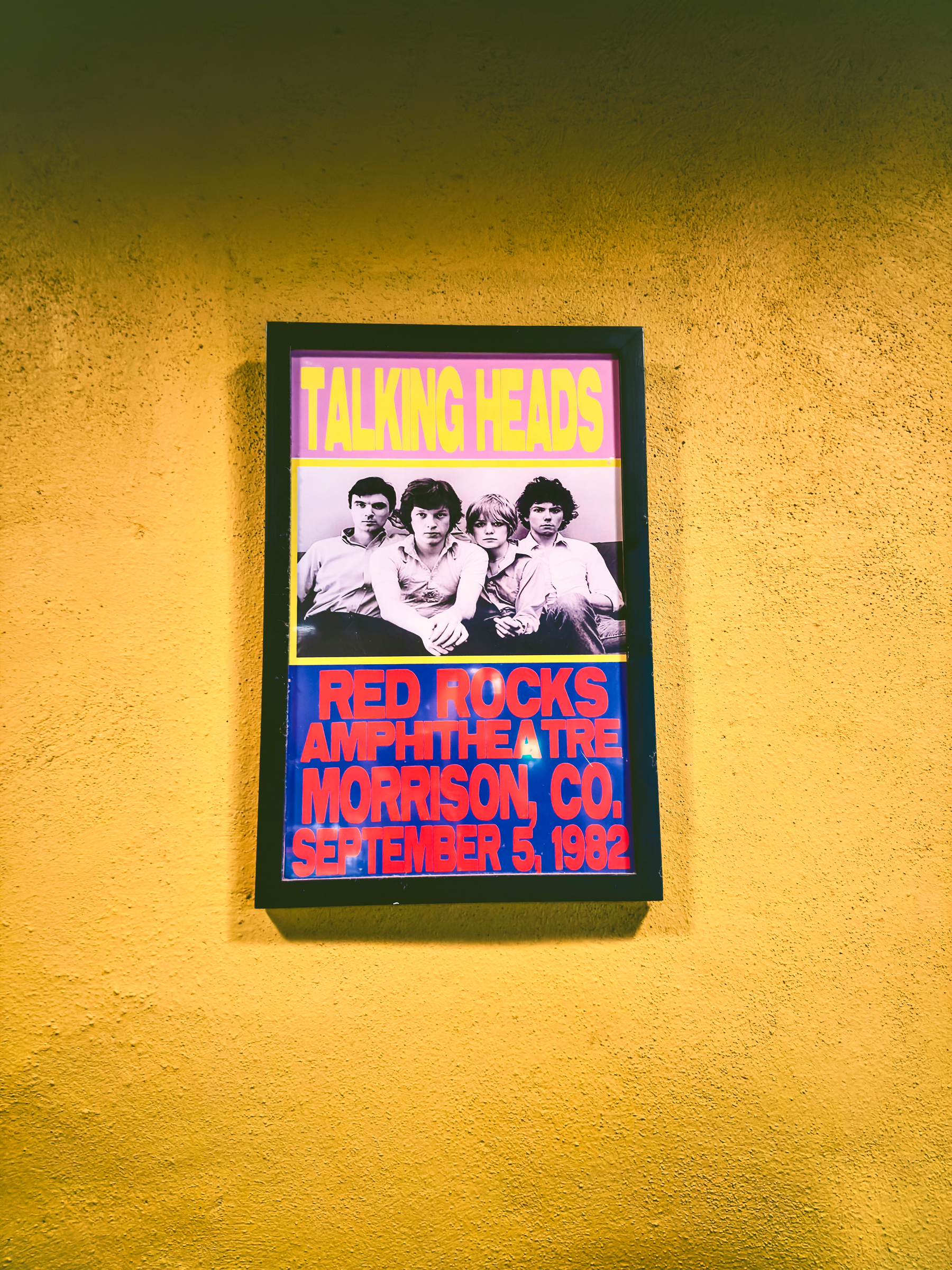Auto-generated description: A vintage concert poster features the band Talking Heads with bold text detailing their performance at Red Rocks Amphitheatre in Morrison, Colorado, on September 5, 1982.