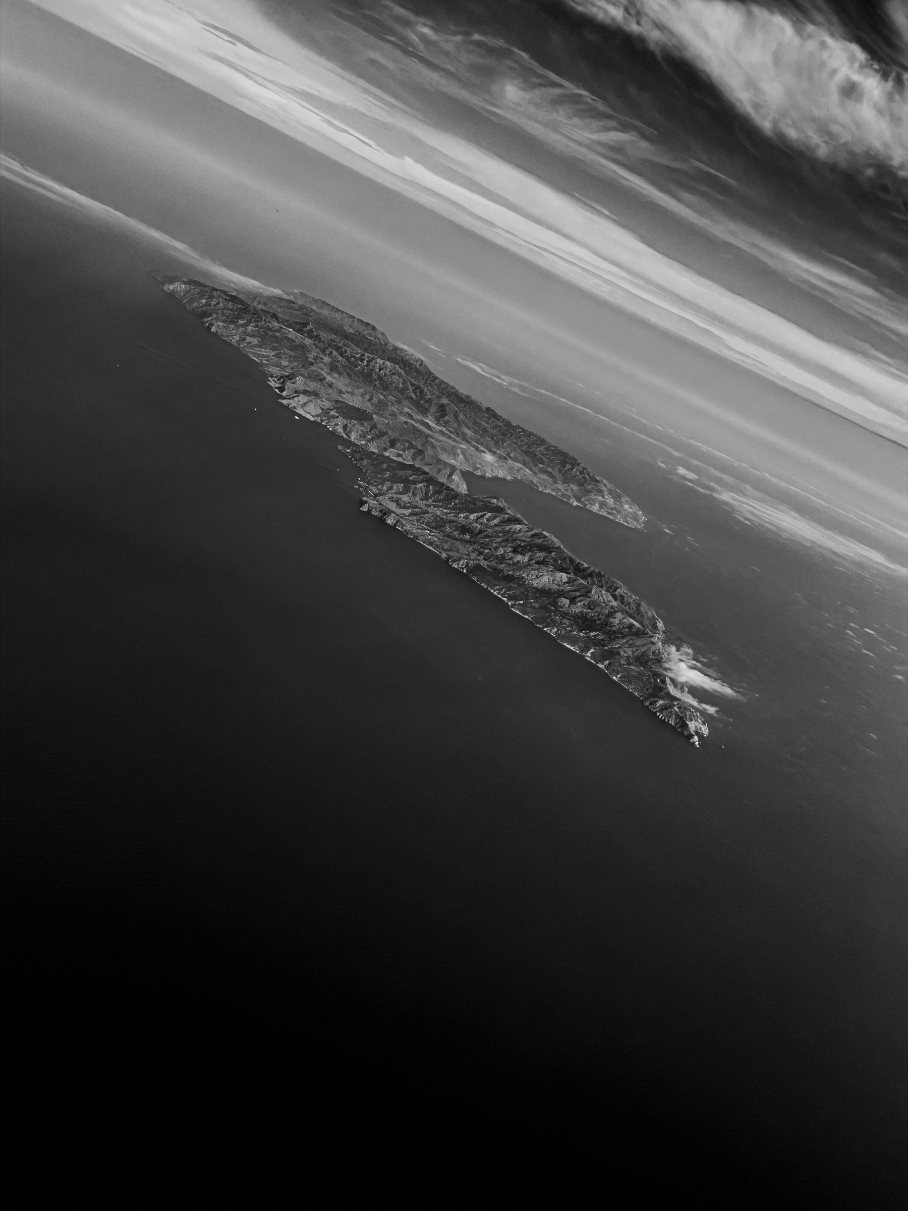 Auto-generated description: A rocky island is surrounded by the ocean under a dramatic sky with layered clouds.