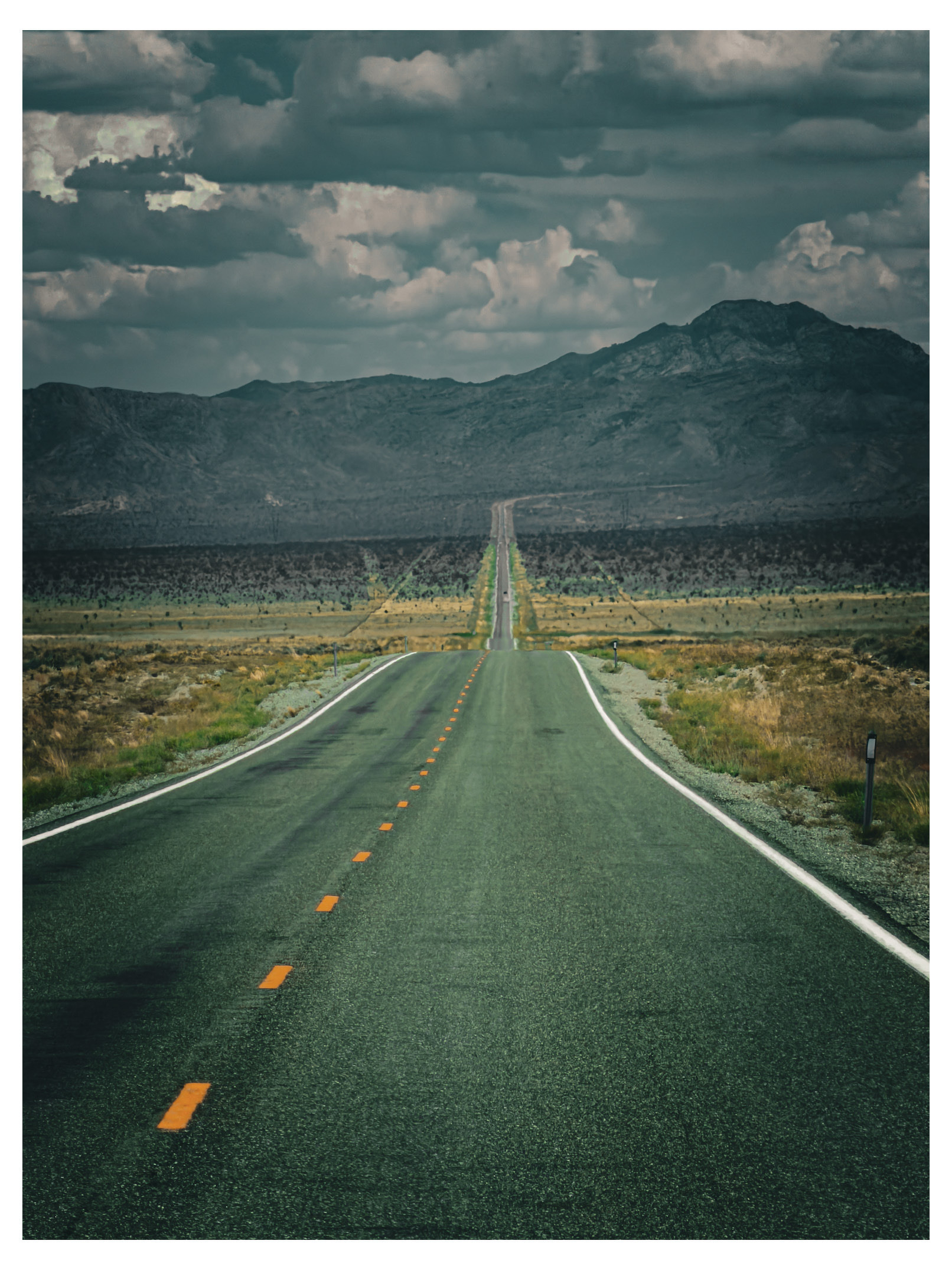 Auto-generated description: A long, empty road stretches straight through a barren desert landscape towards distant mountains under a cloudy sky.
