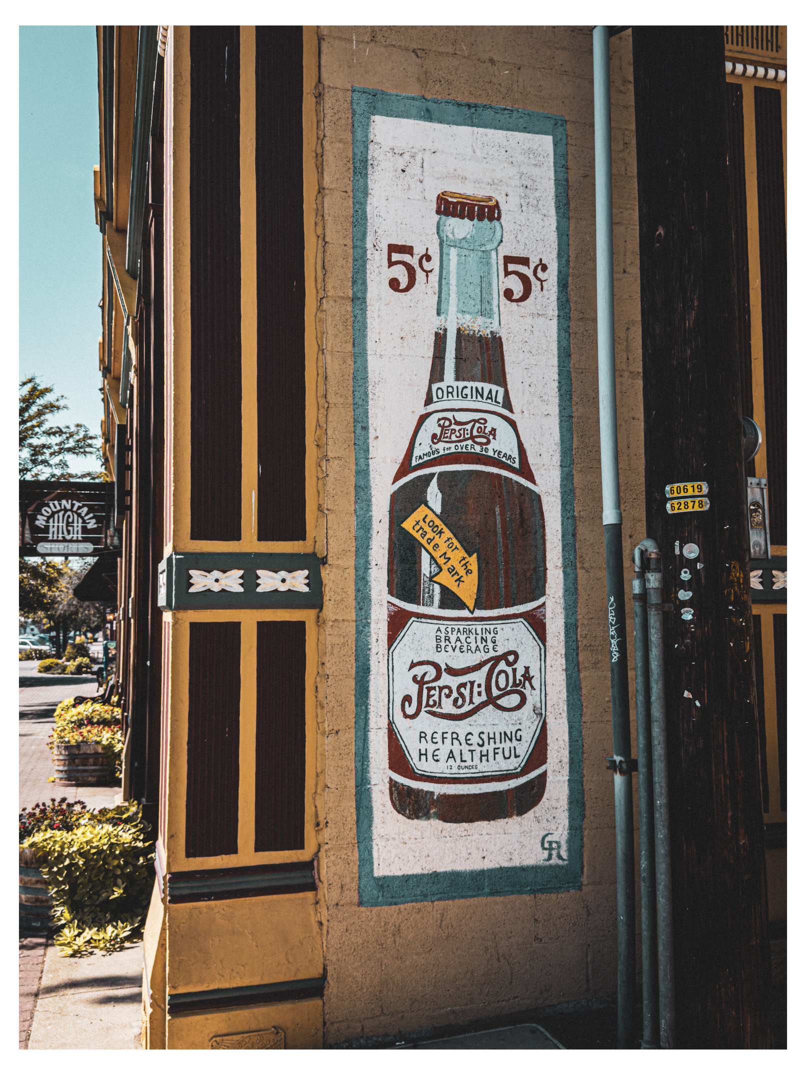 Auto-generated description: A vintage Pepsi-Cola advertisement painted on a wall features a bottle with a 5¢ price, emphasizing it as a refreshing and healthful beverage.