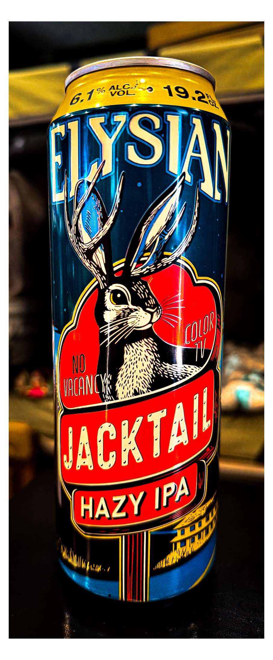 Auto-generated description: A can of Elysian Jacktail Hazy IPA beer with a colorful illustration of a jackrabbit with antlers and the text No Vacancy and Color TV is shown.