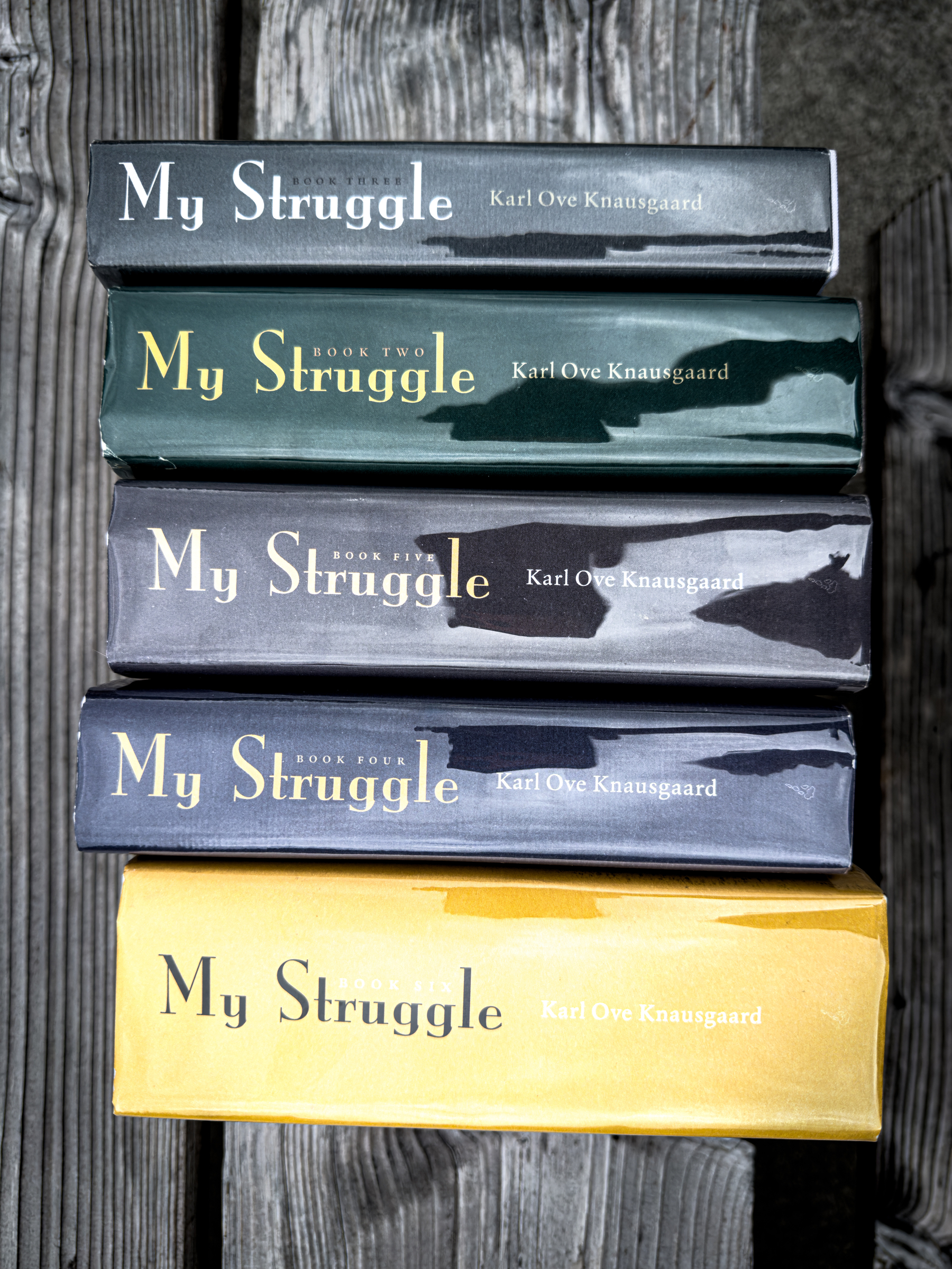 Auto-generated description: A collection of five hardcover books titled My Struggle by Karl Ove Knausgaard is stacked on a wooden surface.