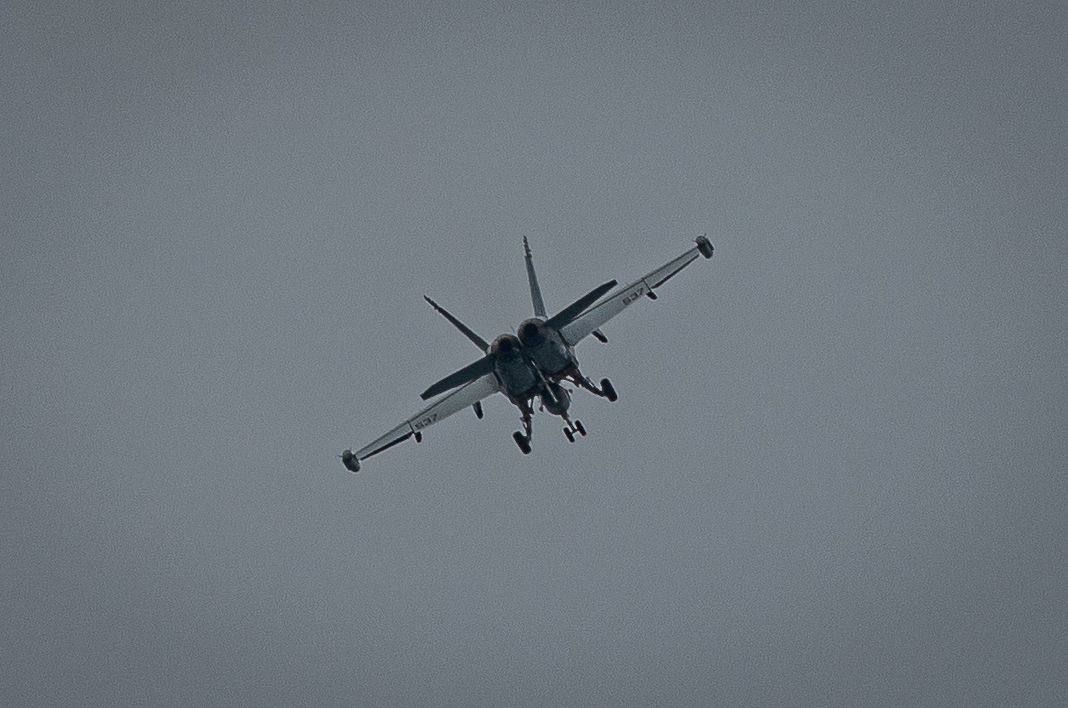 Auto-generated description: A military jet aircraft is flying in the sky with its landing gear extended.